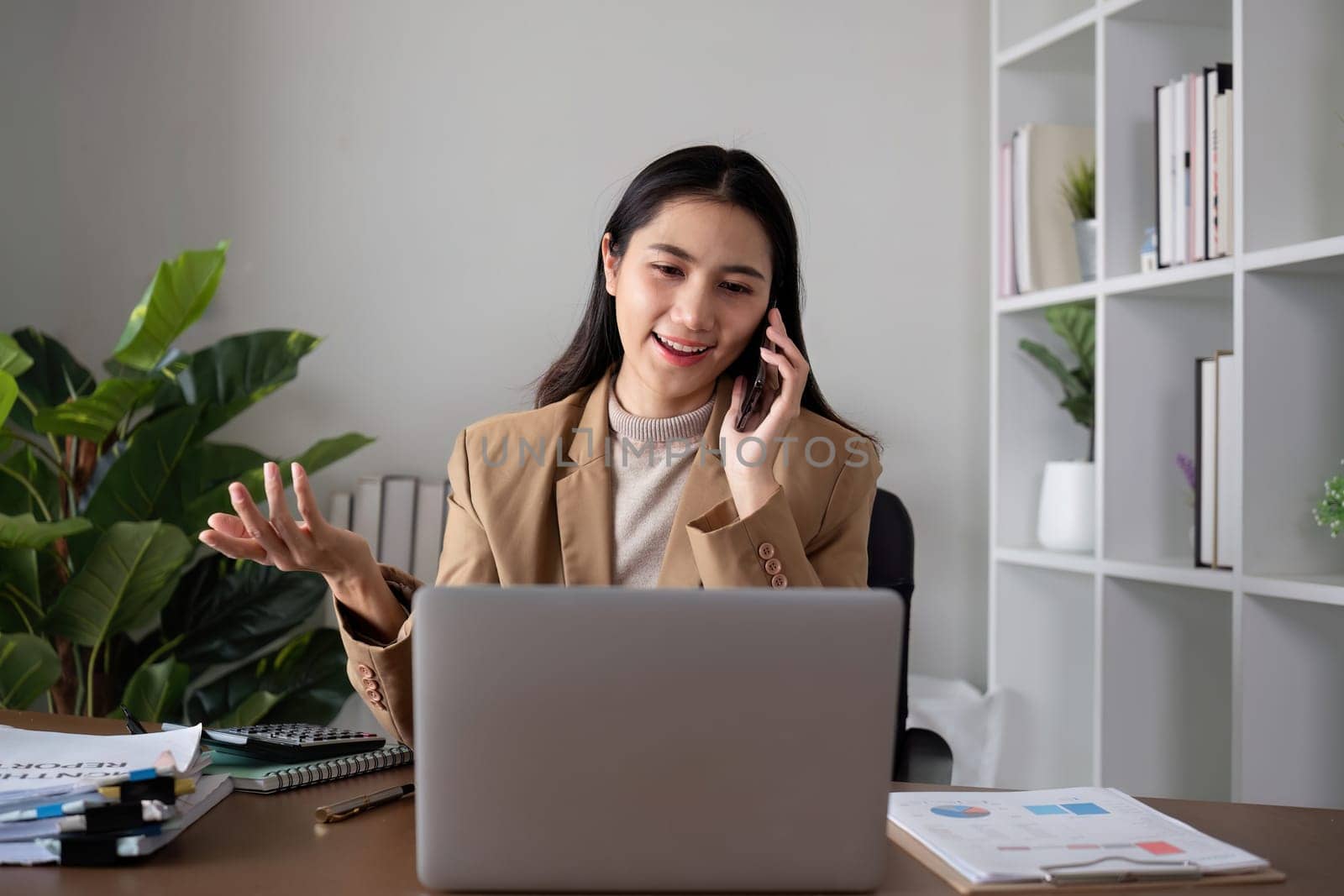 Unhappy Asian business woman shows stress over unsuccessful business while working in home office decorated with soothing green plants..