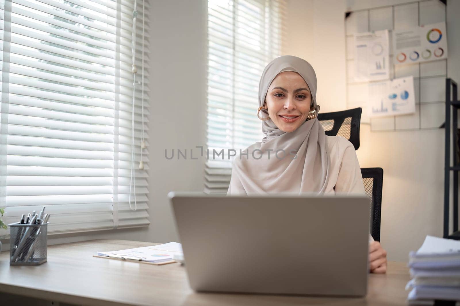 Attractive Muslim accounting business woman working using laptop in modern office.