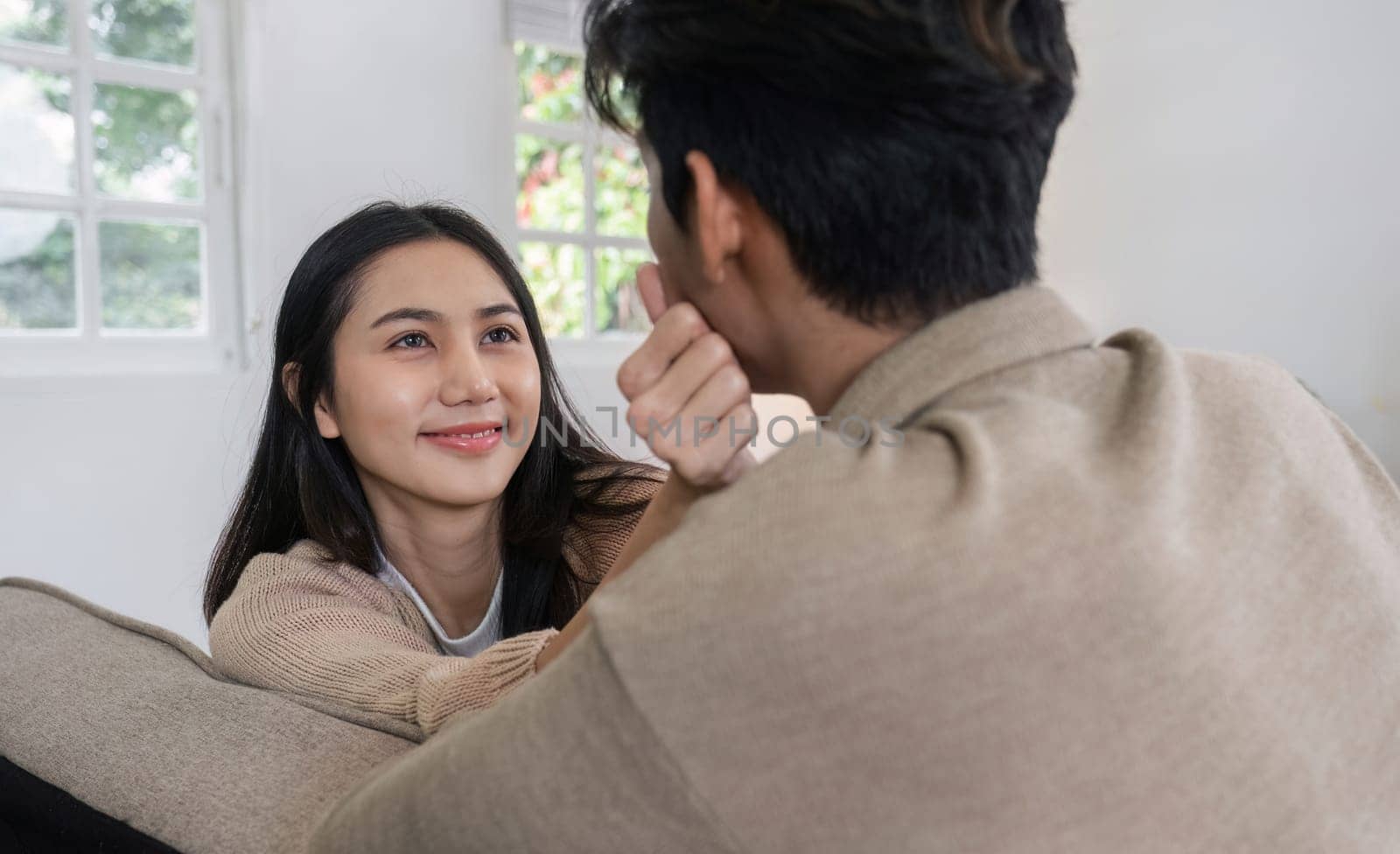 Young couple sitting together on the sofa looking into each other's eyes with love and romance..