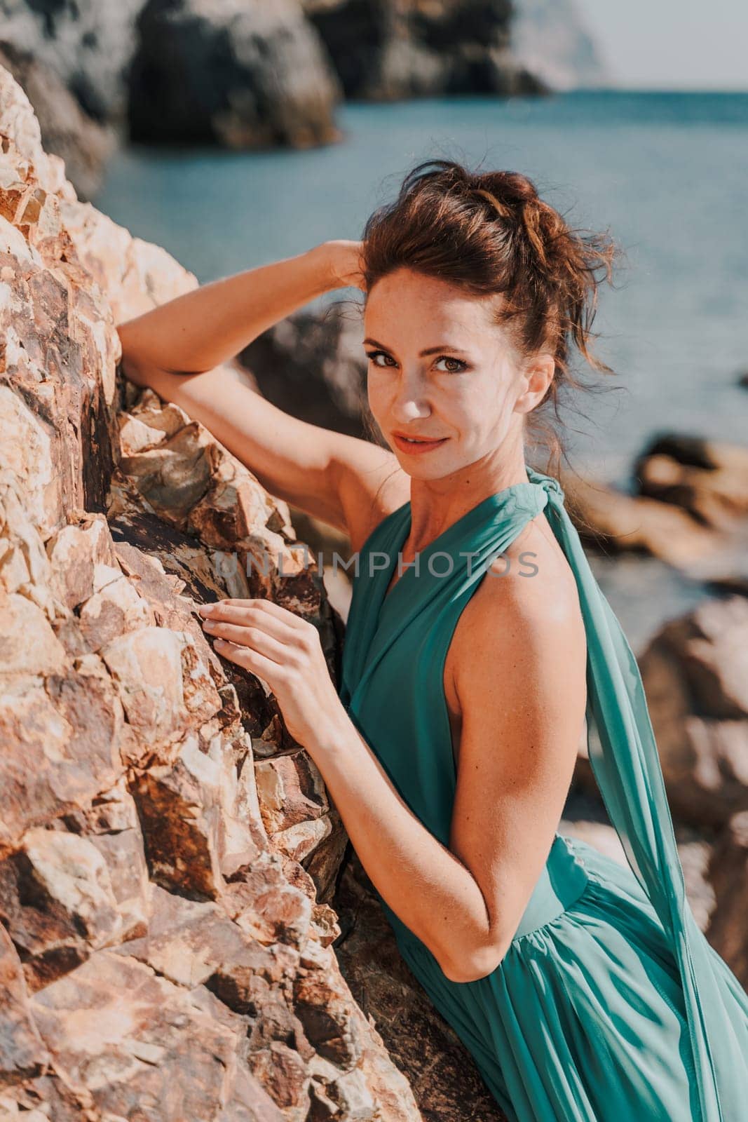 Woman green dress sea. Woman in a long mint dress posing on a beach with rocks on sunny day. Girl on the nature on blue sky background. by Matiunina