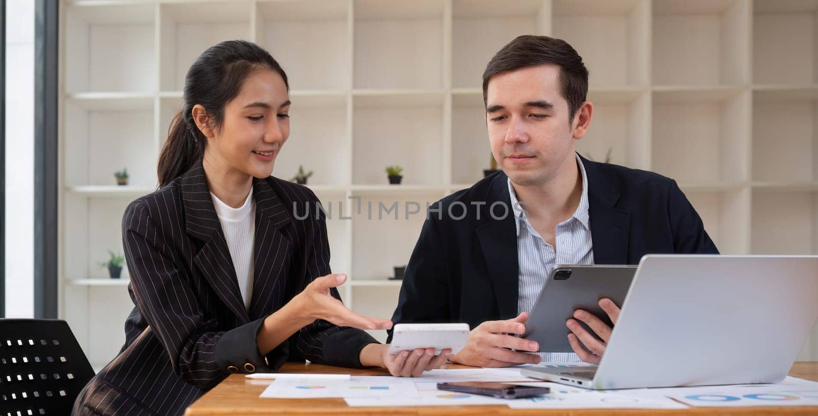 Two businessmen discussing project at the office room Businessman discusses project planning with colleagues in modern workplace while having discussion and advice on financial data report. by wichayada