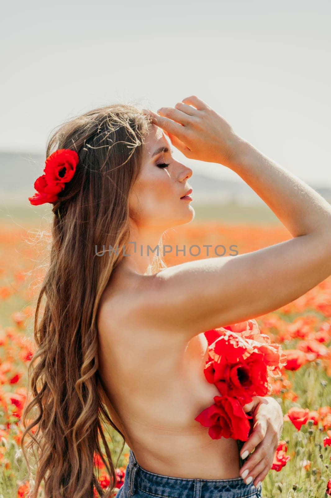 Woman poppies field. portrait of a happy woman with long hair in a poppy field and enjoying the beauty of nature in a warm summer day