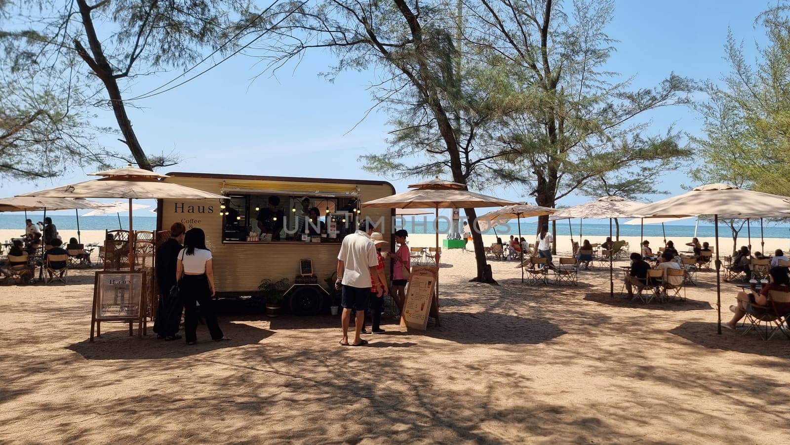 A diverse group of people of various ages and ethnicities stand around a vibrant food truck, chatting, laughing, and enjoying delicious street food as the sun sets in the background by fokkebok