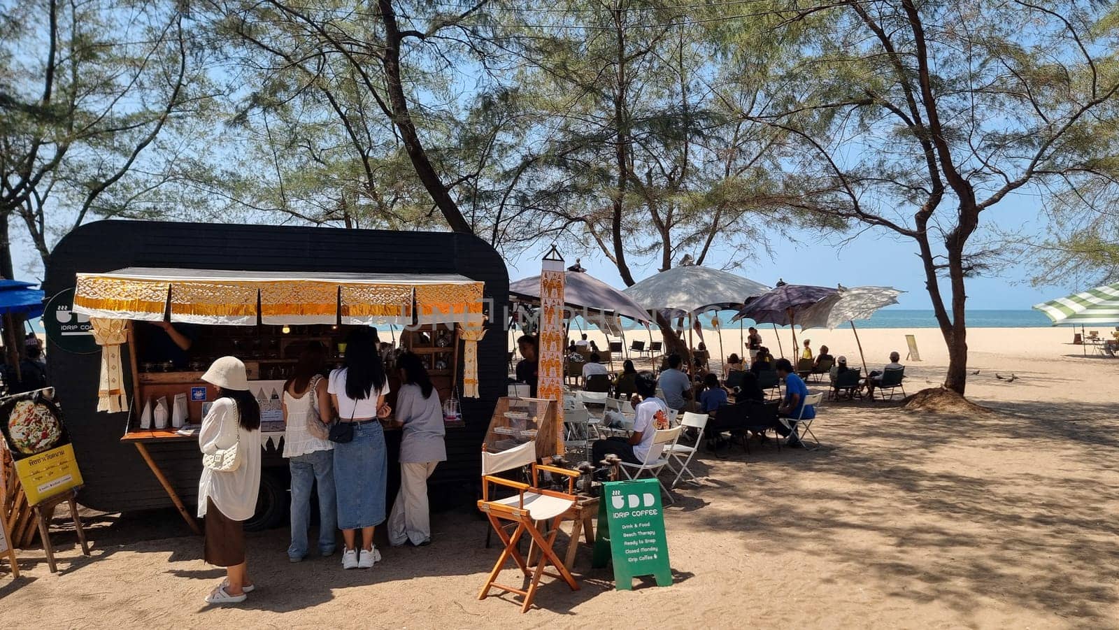 Rayong Thailand 13 March 2024, A group of people stand together on the sandy beach, each holding a colorful umbrella above their heads to shield from the sun.