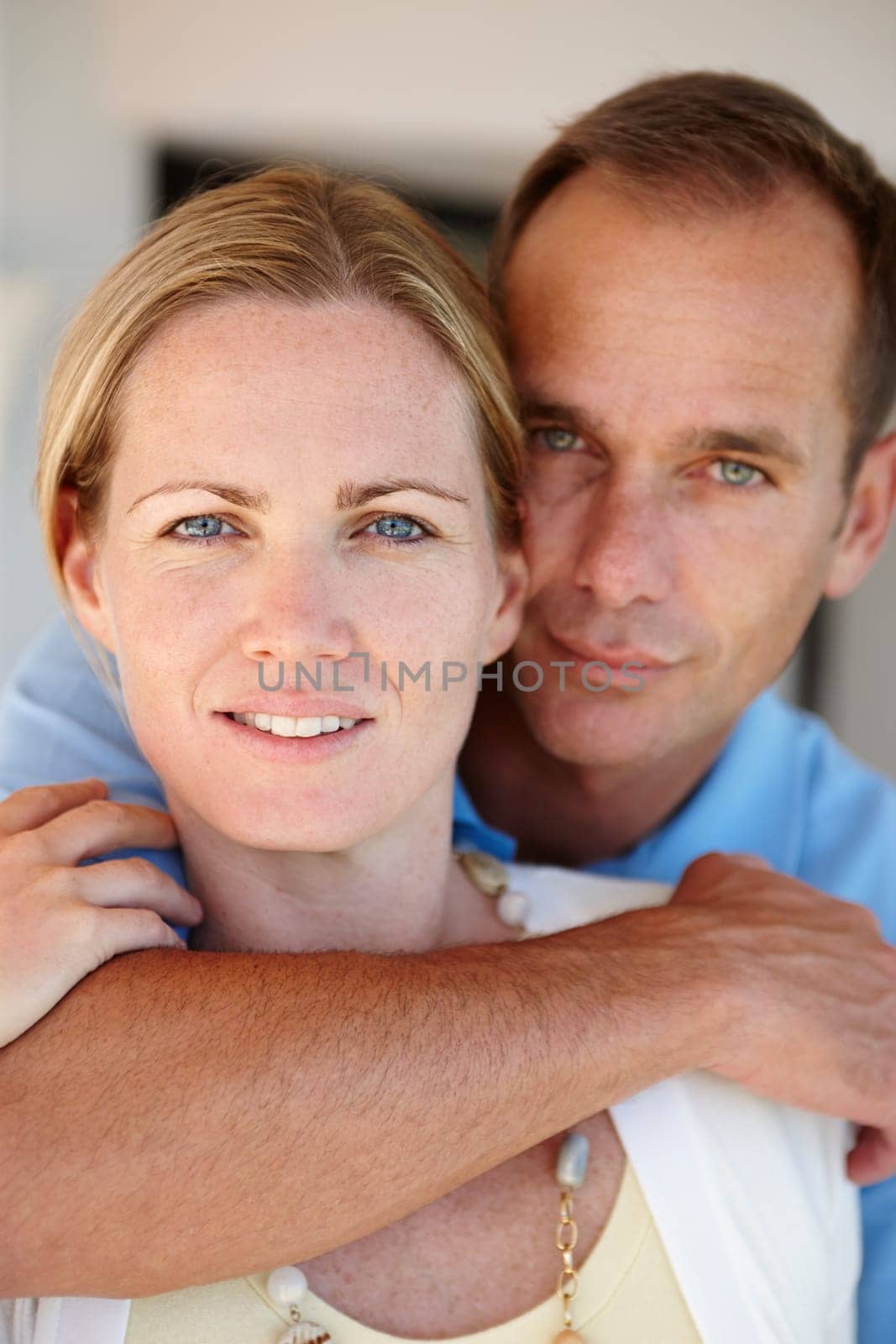 Home, portrait and couple in hug for care, love and proud of marriage milestone on anniversary. Lounge, embrace and people for relationship achievement, romance and bonding in apartment for support by YuriArcurs
