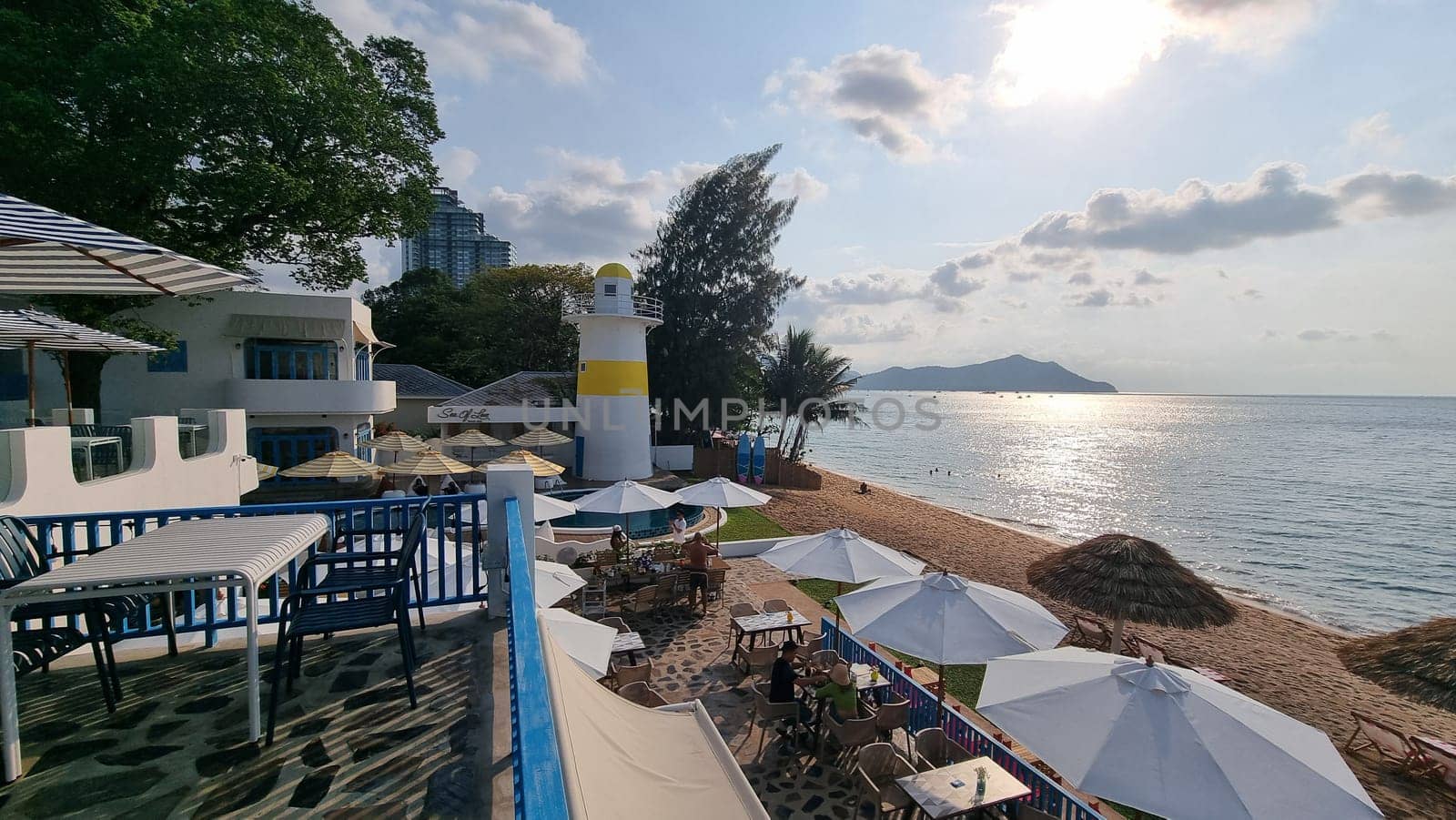 Relaxing day at the beach with colorful umbrellas and chairs dotting the sandy shoreline, inviting visitors to unwind and enjoy the ocean view by fokkebok