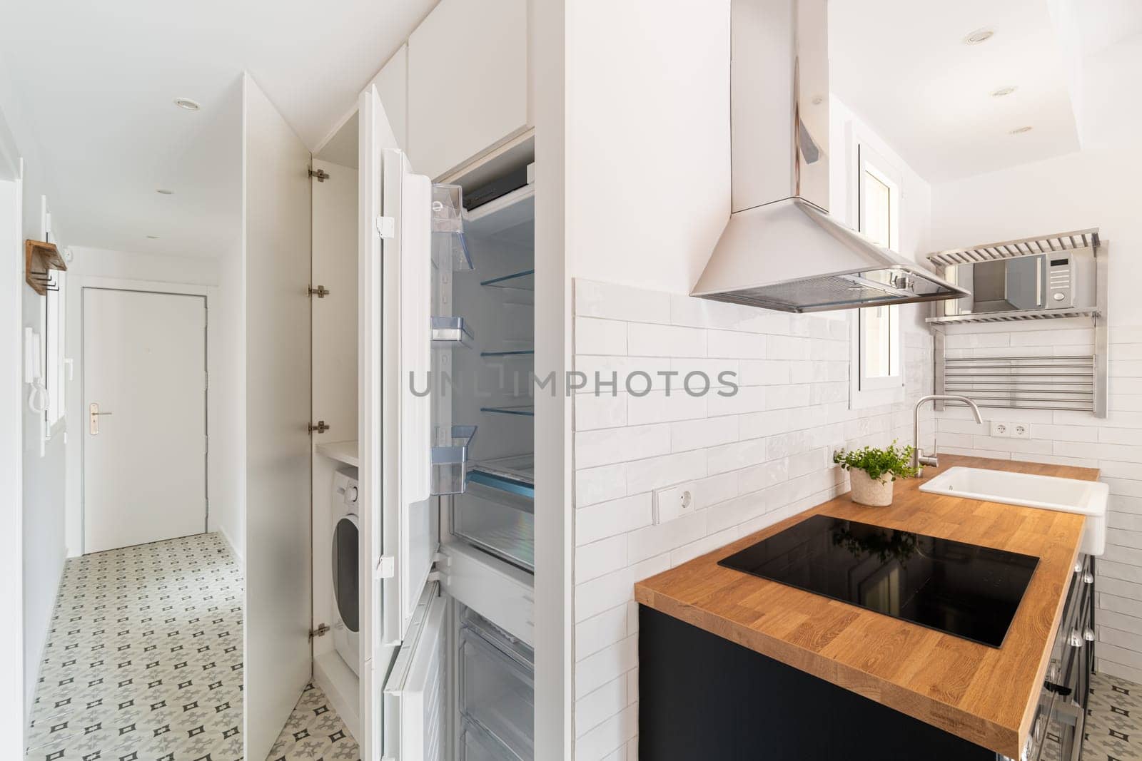 View of the kitchen and corridor with a washing machine and a built-in refrigerator compact but comfortable apartment in a new building. Mortgage house for a young family.