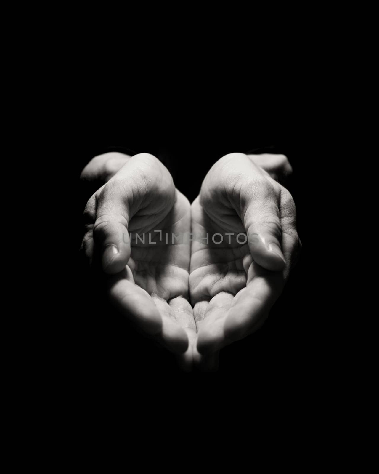Two hands open facing up in a dark background, implying an offering or gesture
