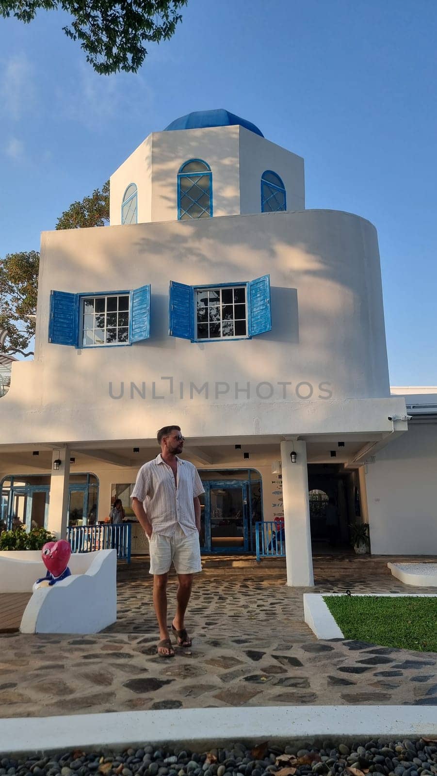 Bangsaray Pattaya Thailand 28 February 2024,A man in casual attire stands confidently in front of a majestic white building, the sunlight casting a warm glow over the scene.