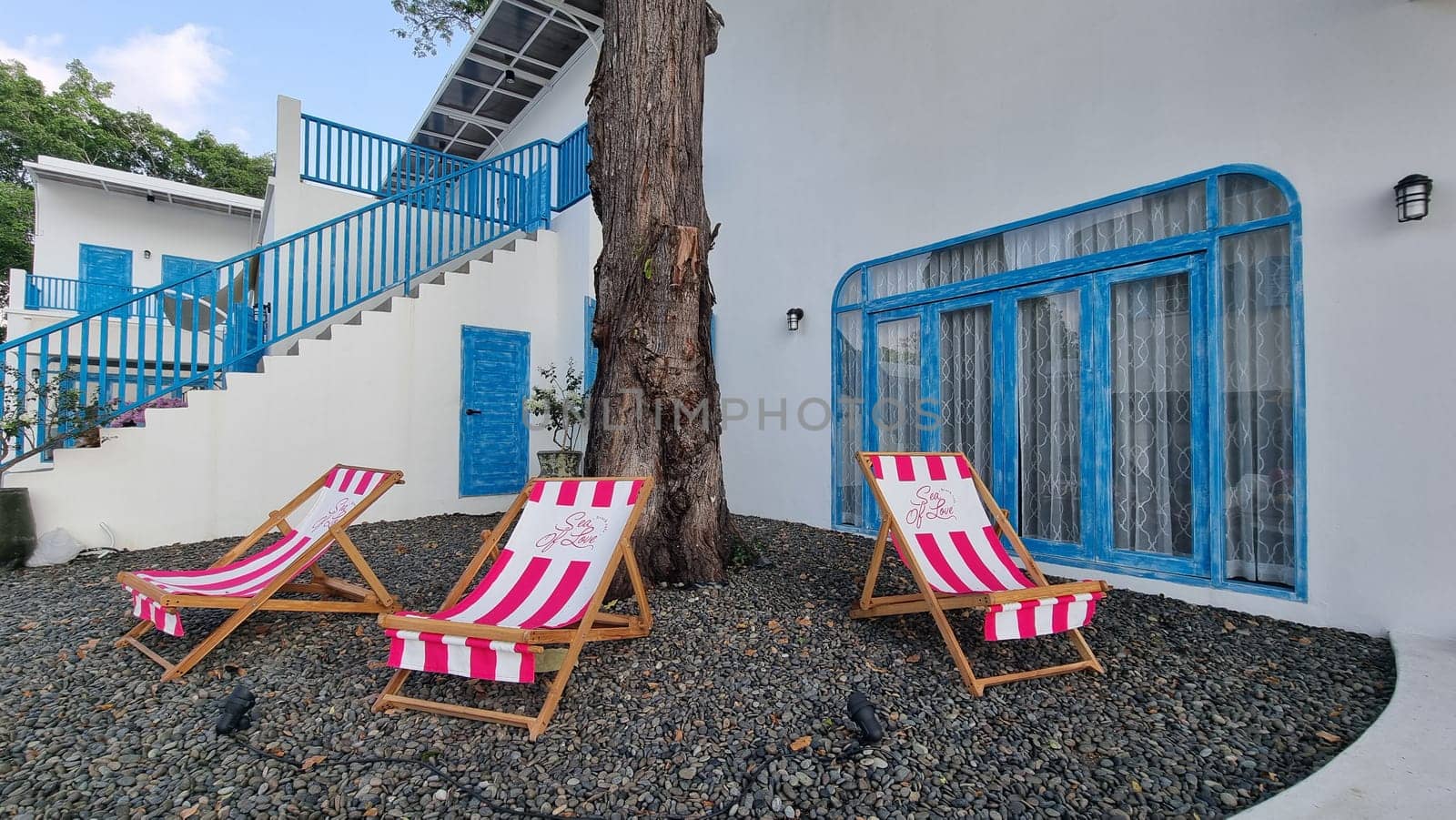 Two lawn chairs are peacefully resting next to a tree, creating a serene spot for relaxation and enjoying nature by fokkebok