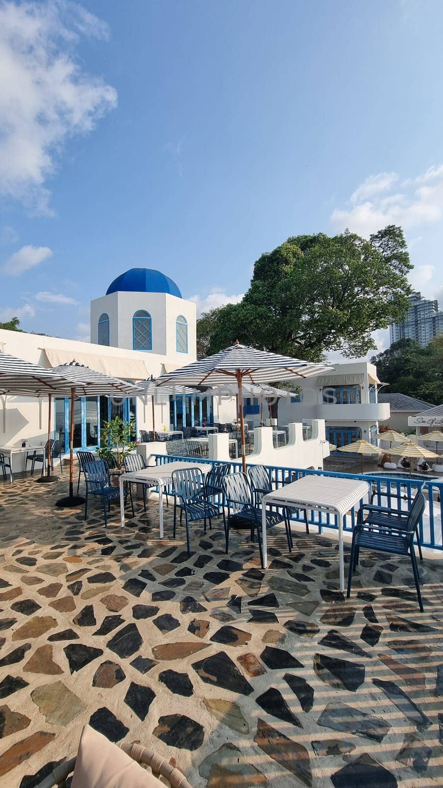 A peaceful patio area with tables and chairs set against a serene blue dome in the background by fokkebok
