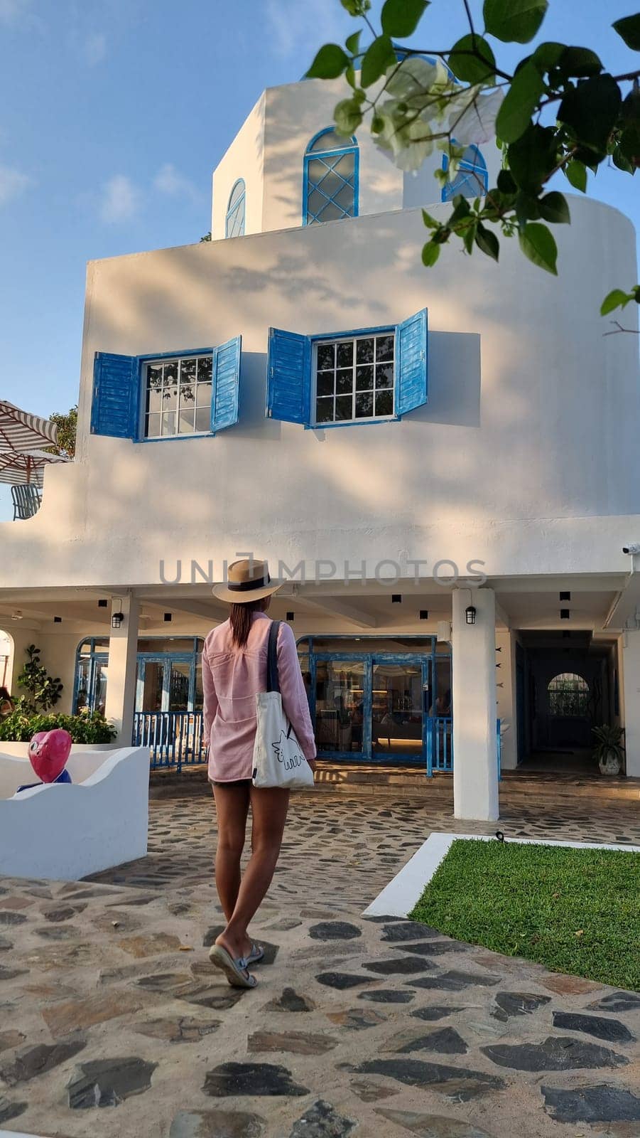 A stylish woman stands gracefully outside a pristine white building, exuding confidence and poise against the architectural backdrop by fokkebok