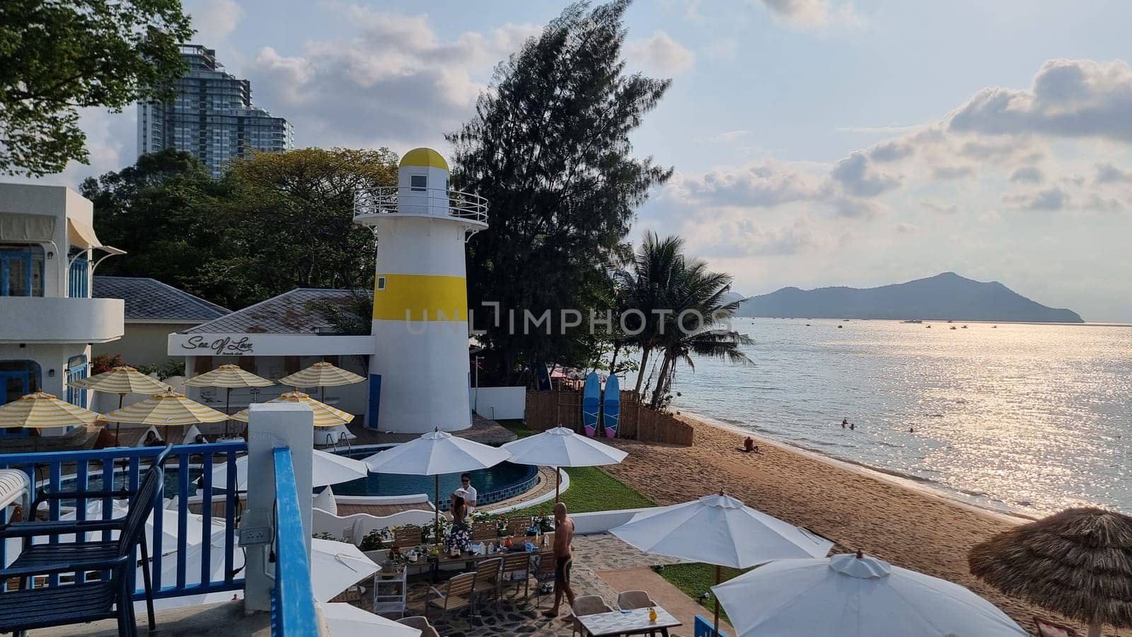 A scenic beachfront view adorned with colorful umbrellas and beach chairs, inviting you to relax under the sun and enjoy the soothing sound of the waves crashing against the shore by fokkebok