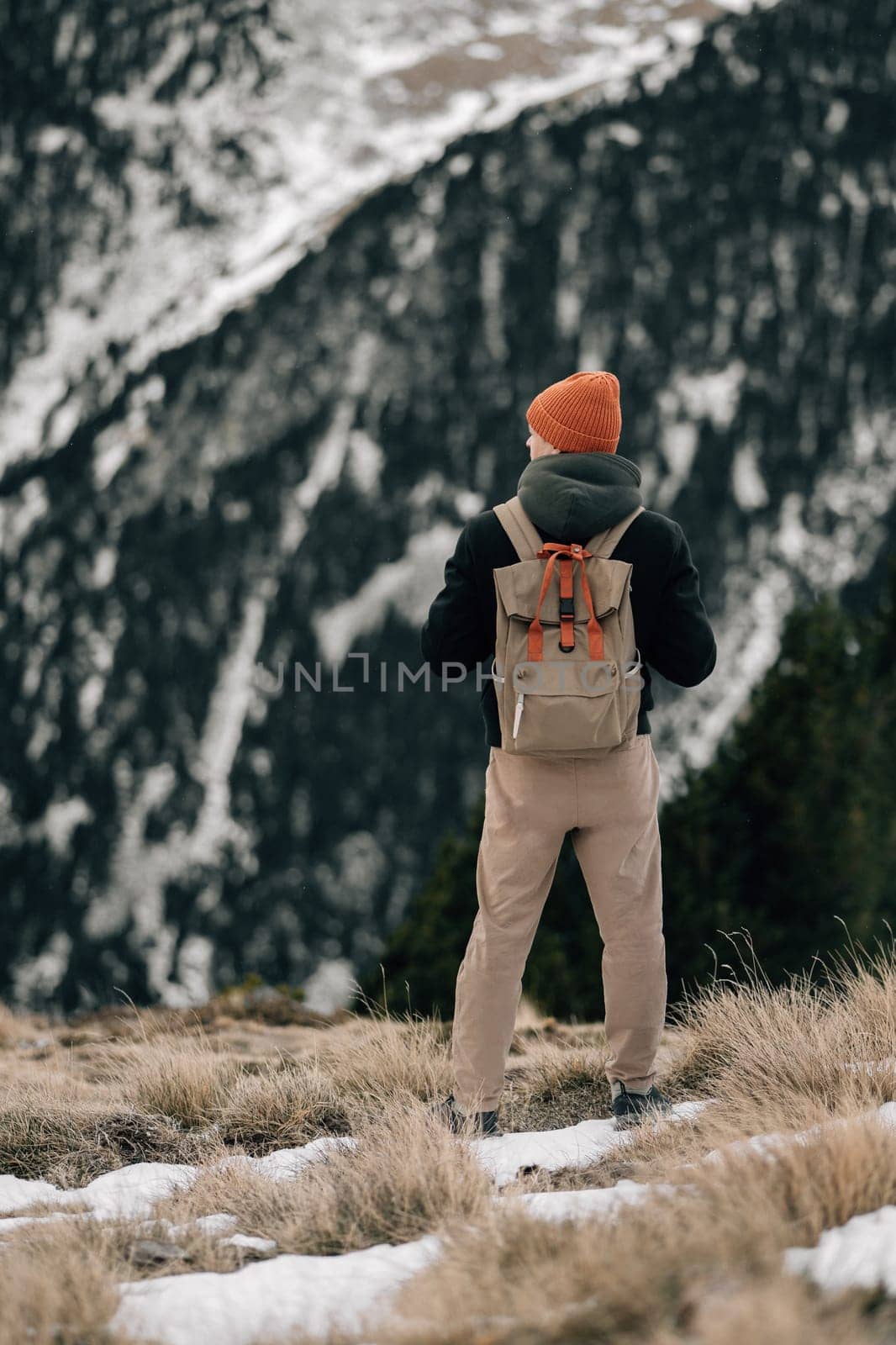 An adventurer gazes at majestic snow-capped mountains, evoking a sense of solitude and contemplation.