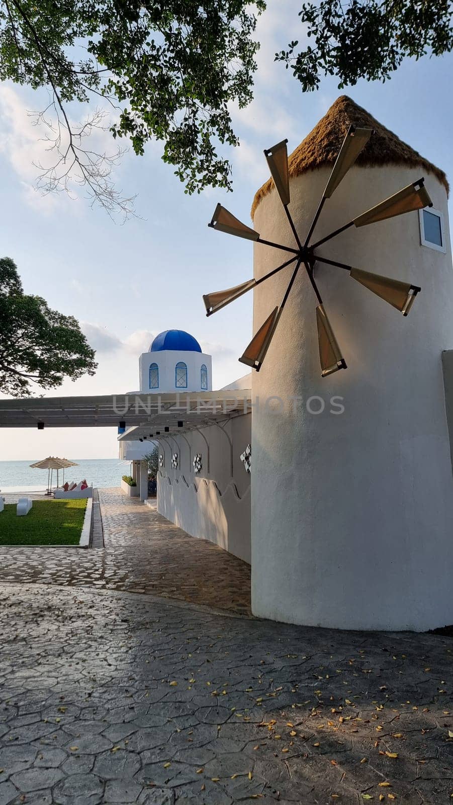 A majestic white building stands tall with a windmill spinning gracefully on top, capturing the essence of a European countryside by fokkebok