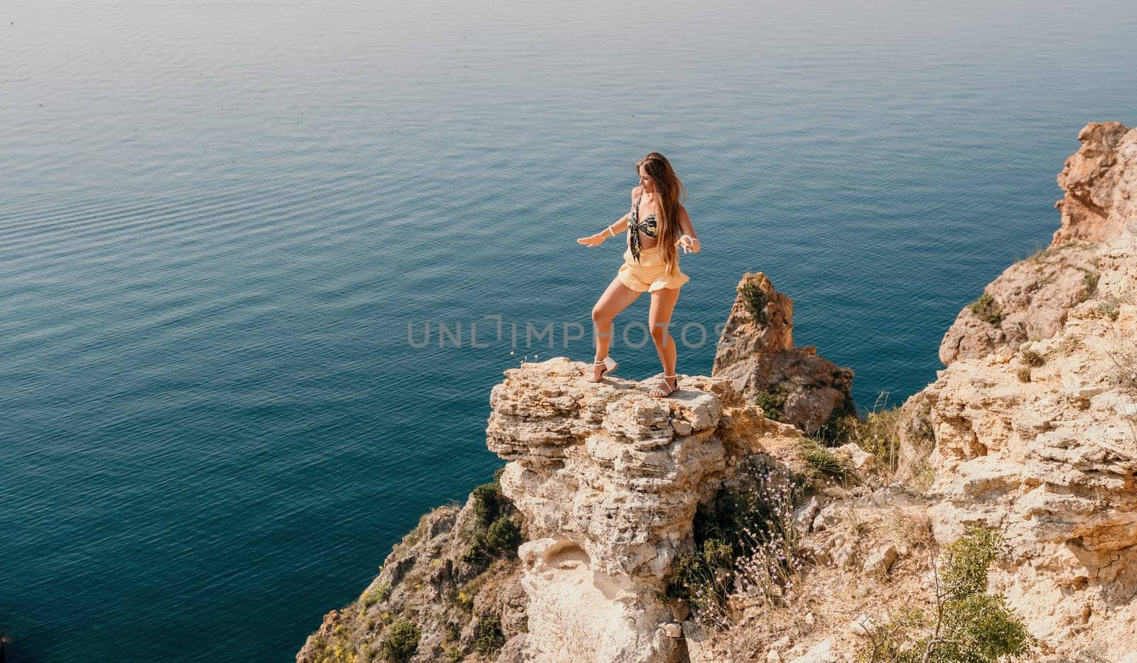 Woman travel sea. Happy tourist enjoy taking picture outdoors for memories. Woman traveler looks at the edge of the cliff on the sea bay of mountains, sharing travel adventure journey by panophotograph