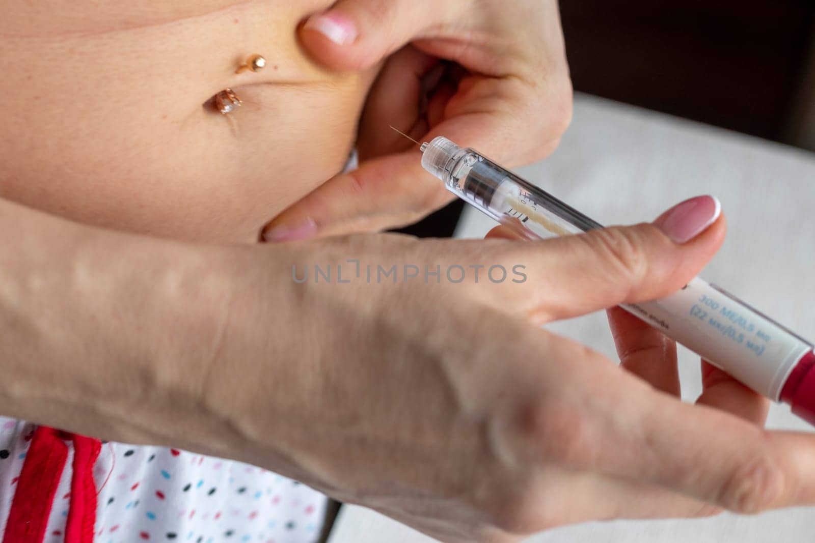 Close up shot of the woman with beautiful hands, preparing hormone medicine and injecting herself to the abdomen with pierced bellybutton.
