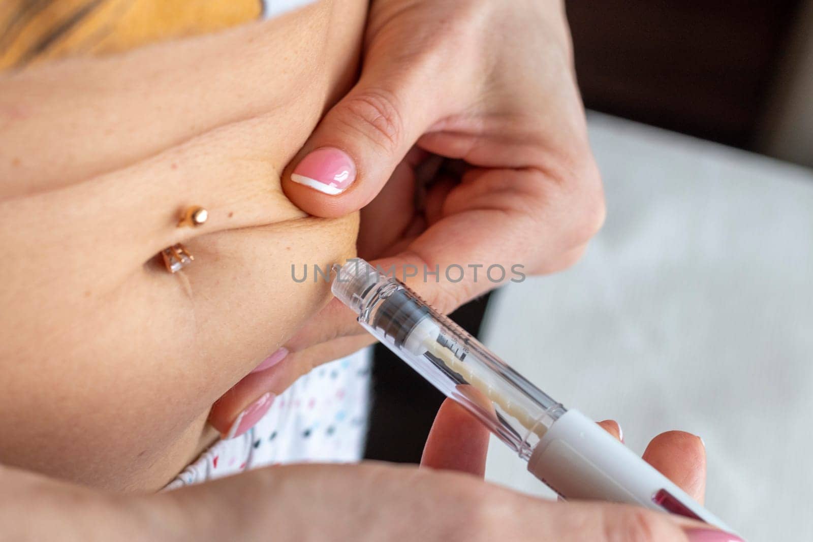 Close up shot of the woman with beautiful hands, preparing hormone medicine and injecting herself to the abdomen with pierced bellybutton.