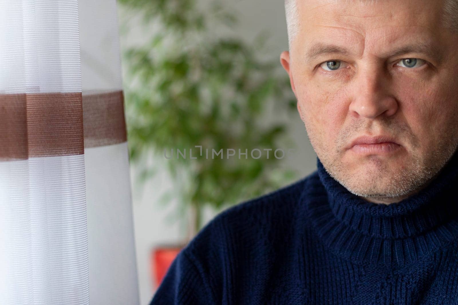 Portrait of the mid aged man with grey hair, wearing warm, dark blue sweater