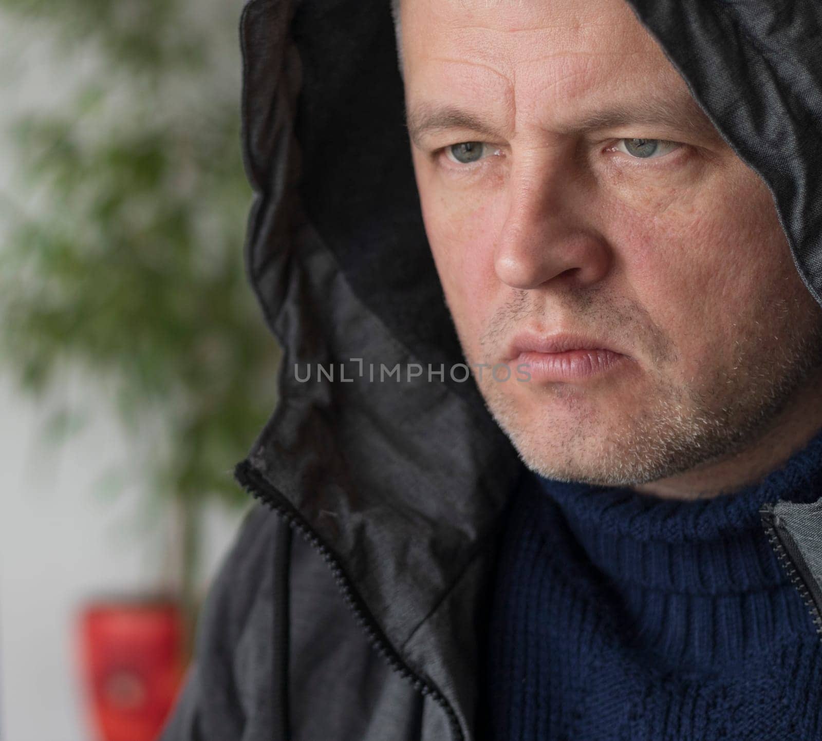 Portrait of the mid aged man with grey hair, wearing warm, dark blue sweater and grey coat.