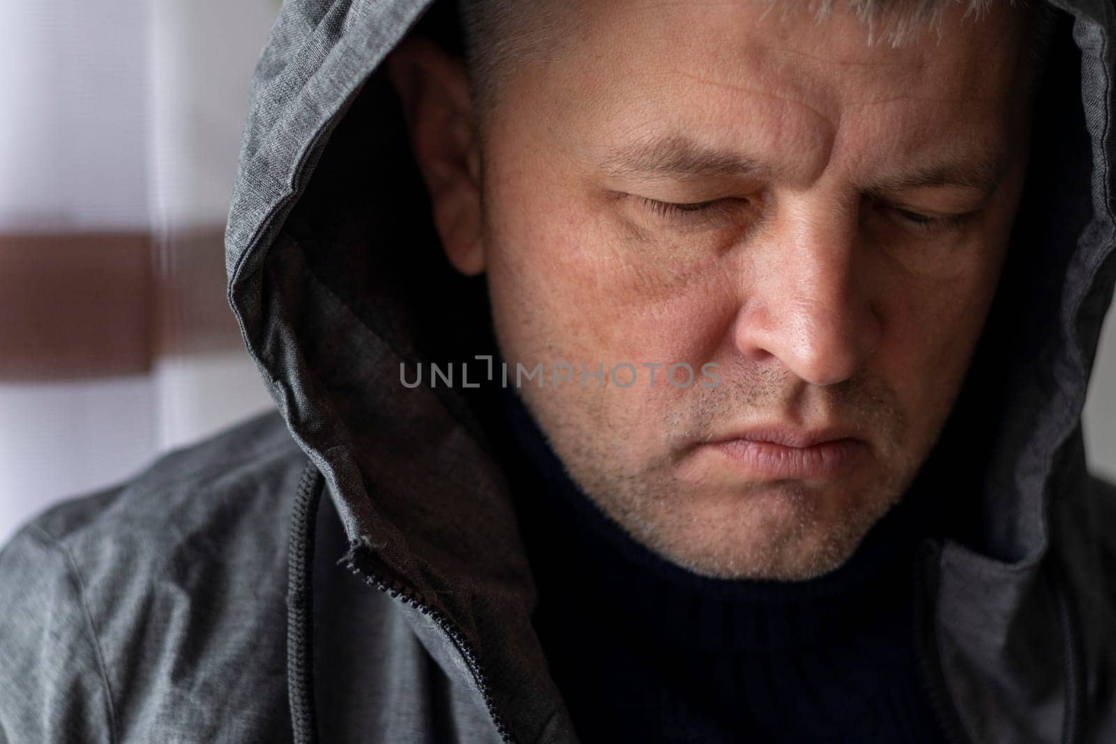 Portrait of the mid aged man with grey hair, wearing warm, dark blue sweater and grey coat.