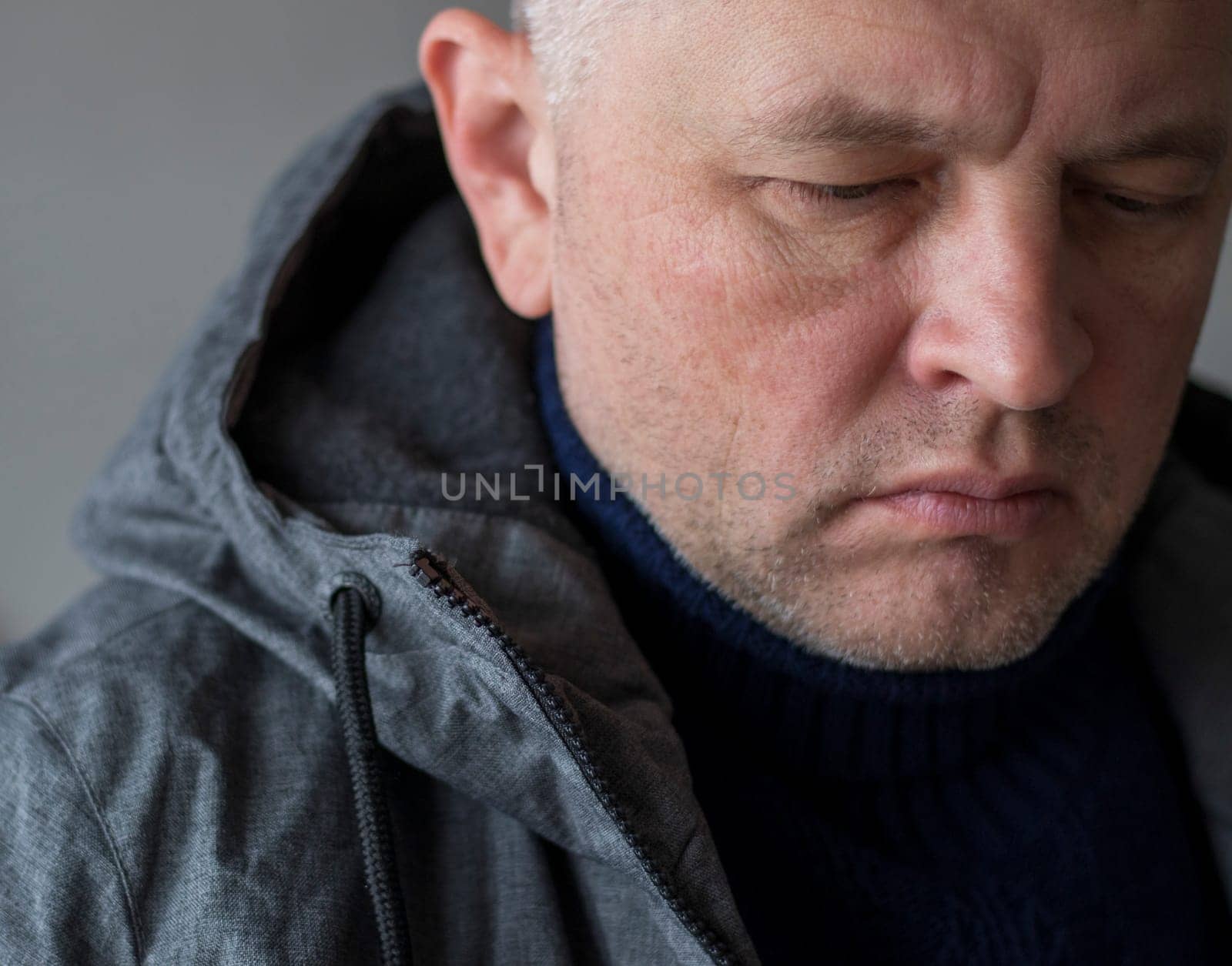 Portrait of the mid aged man with grey hair, wearing warm, dark blue sweater and grey coat.