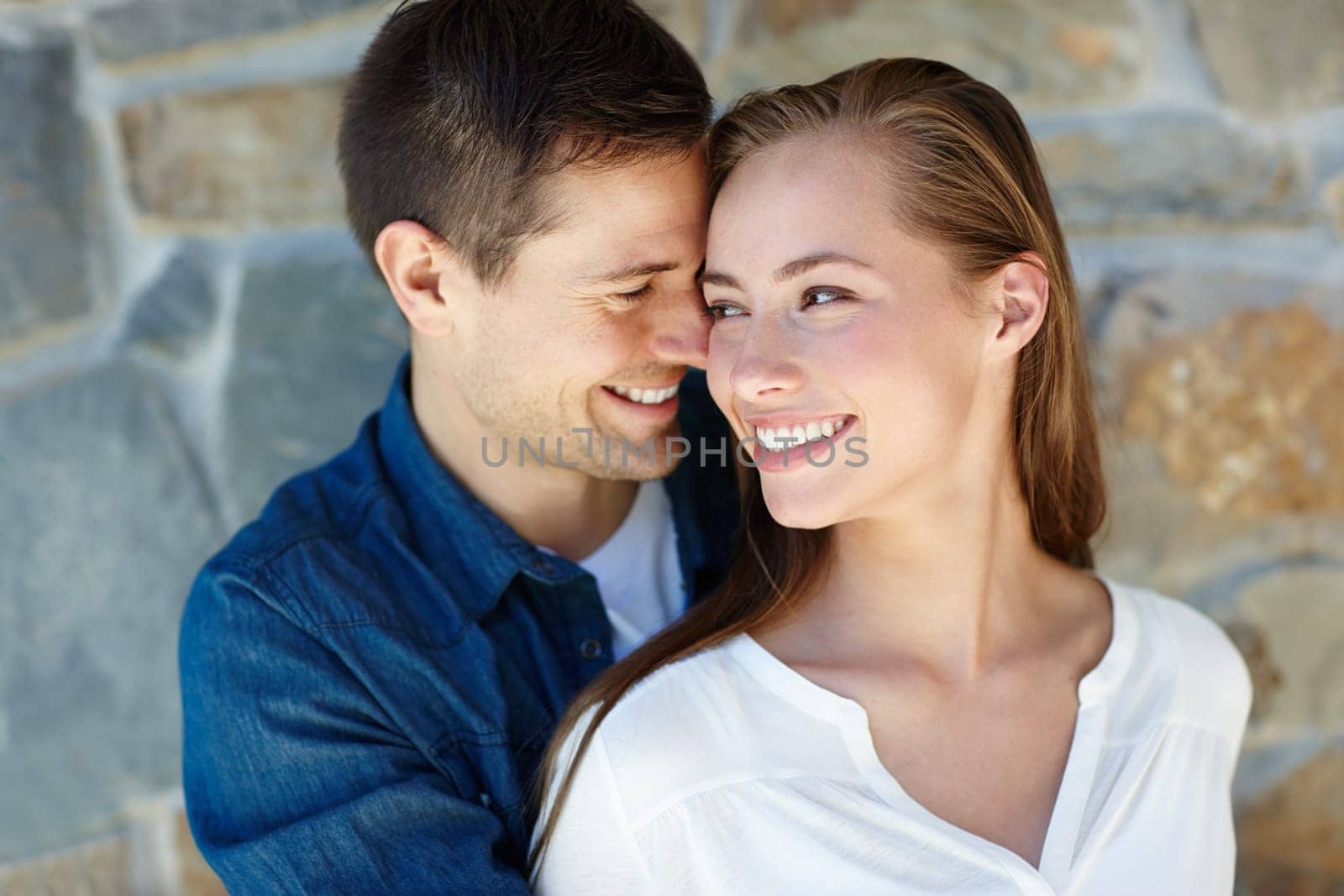 Outdoors, couple and embrace for love, touch and romance or care on wall background. Happy people, relaxing and smile for pride in relationship or commitment, loyalty and connection on holiday.