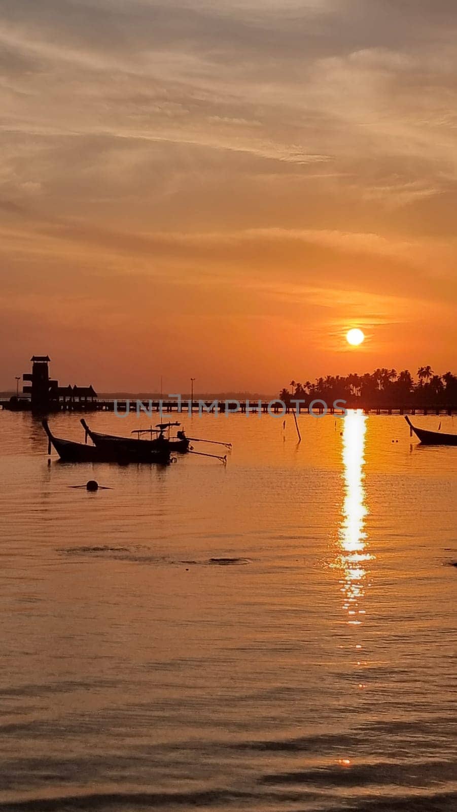 Two elegant boats gracefully float on the calm, glittering surface of the water. Koh Mook Thailand