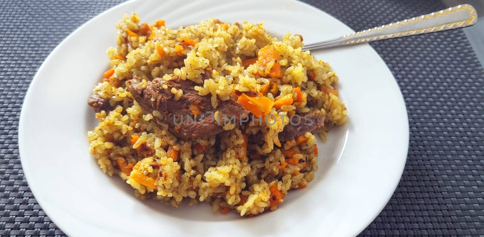 Close up shot of the plov, dish from Uzbel traditional cuisine made of rise carrots and meat