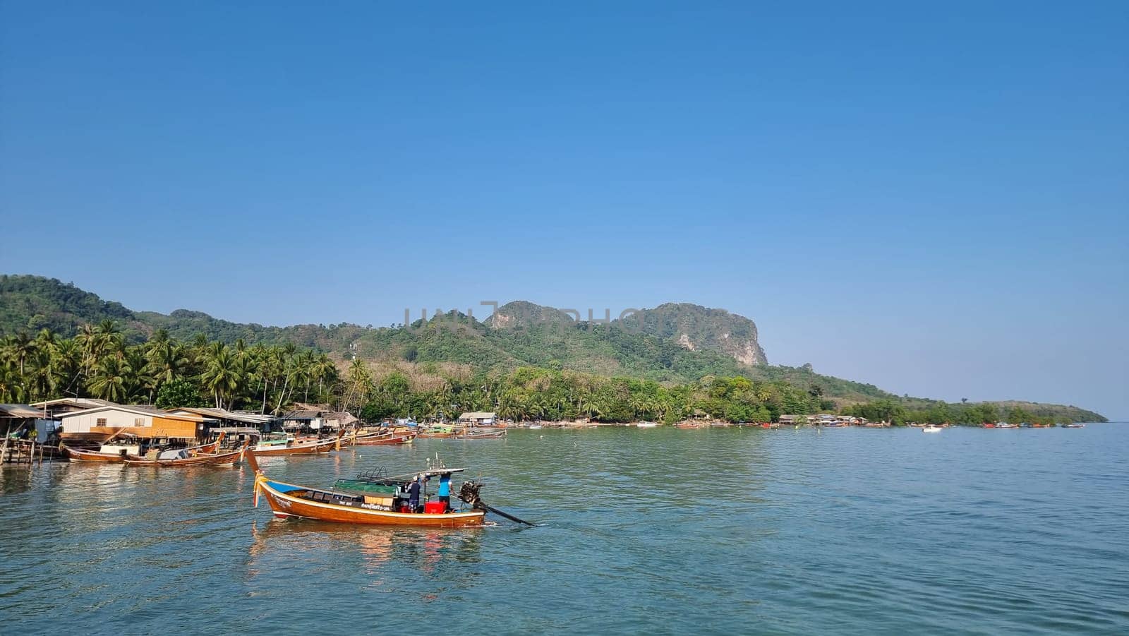 A small boat peacefully floats atop the calm waters of a serene lake, reflecting the clear blue sky above by fokkebok