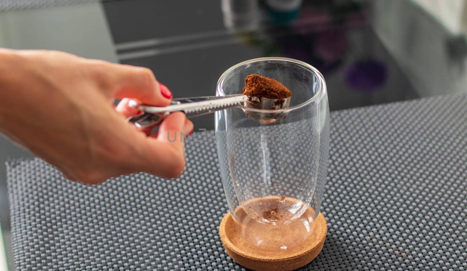 Shot of the ground coffee being added to transparent cup to brew a coffee.