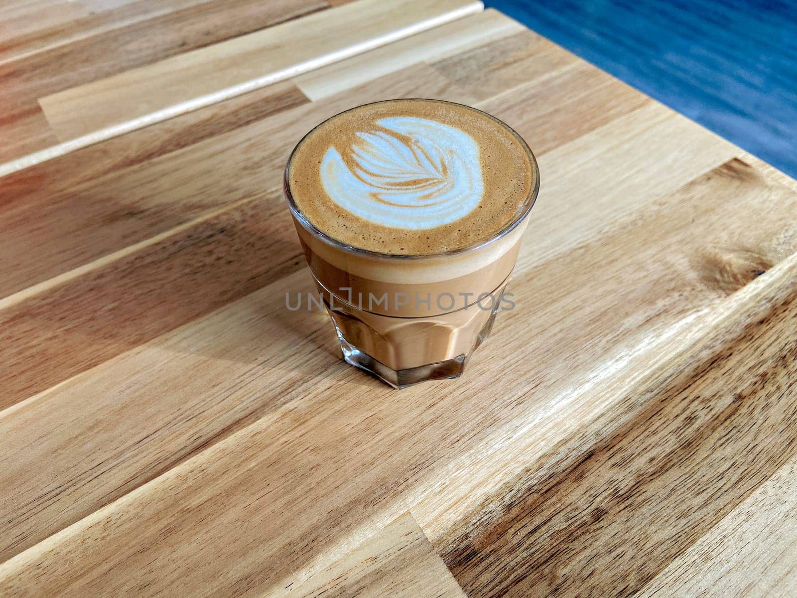 A glass of coffee latte on wooden texture of the table by Imagenet