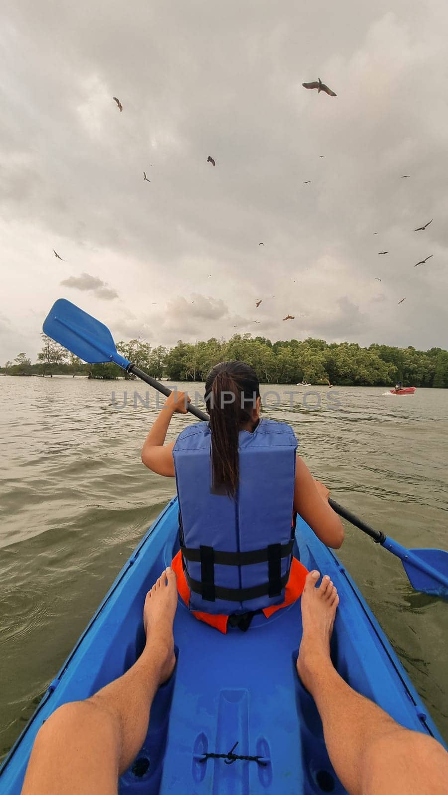 A man and a woman paddle a kayak together on a calm lake, surrounded by peaceful nature. Chantaburi Thailand