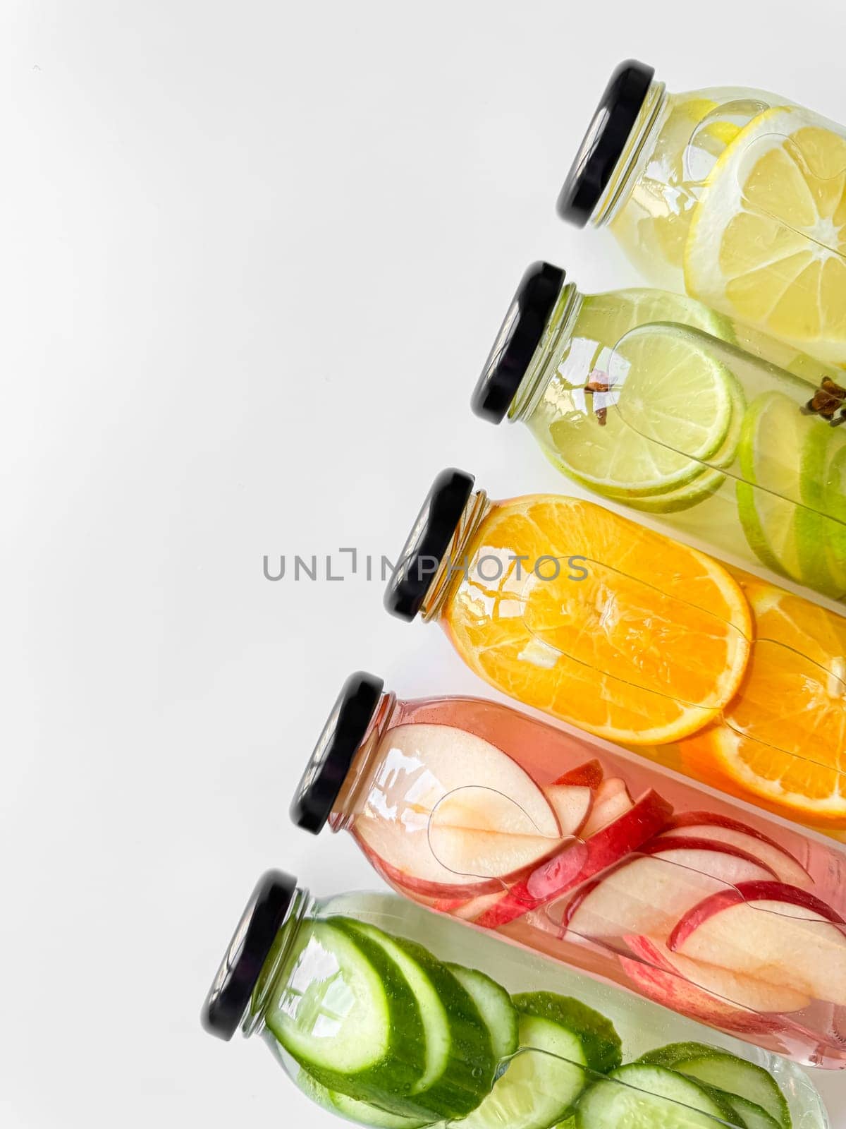 Variety detox drinks in glass bottles on white background, with copy space. Healthy lifestyle and hydration concept for design and print. High quality photo