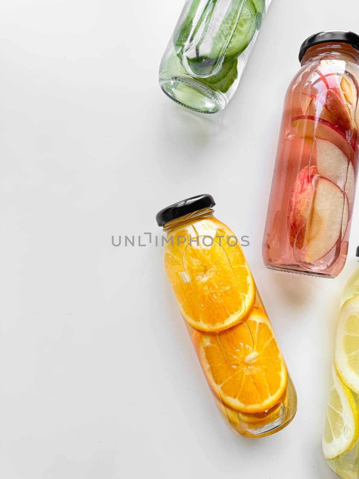 Variety detox drinks in glass bottles on white background, with copy space. Healthy lifestyle and hydration concept for design and print. by Lunnica