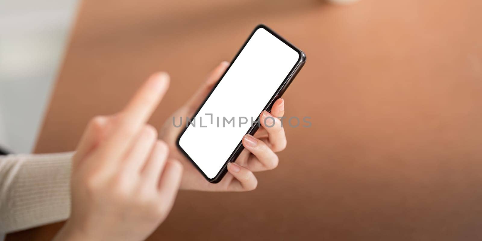Mockup of a woman holding and using mobile phone with blank screen while laying down on the floor with feel relax.