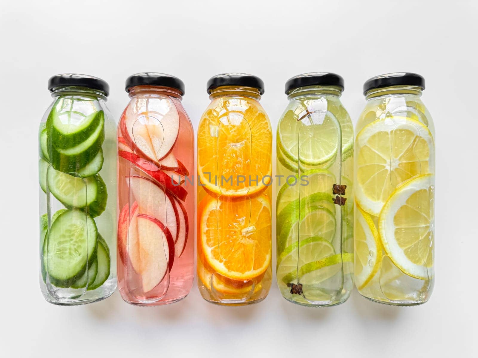 Fruit and vegetable detox drinks in glass bottles on white background. Horizontal line up with copy space. Natural infused water variety concept for healthy lifestyle. High quality photo