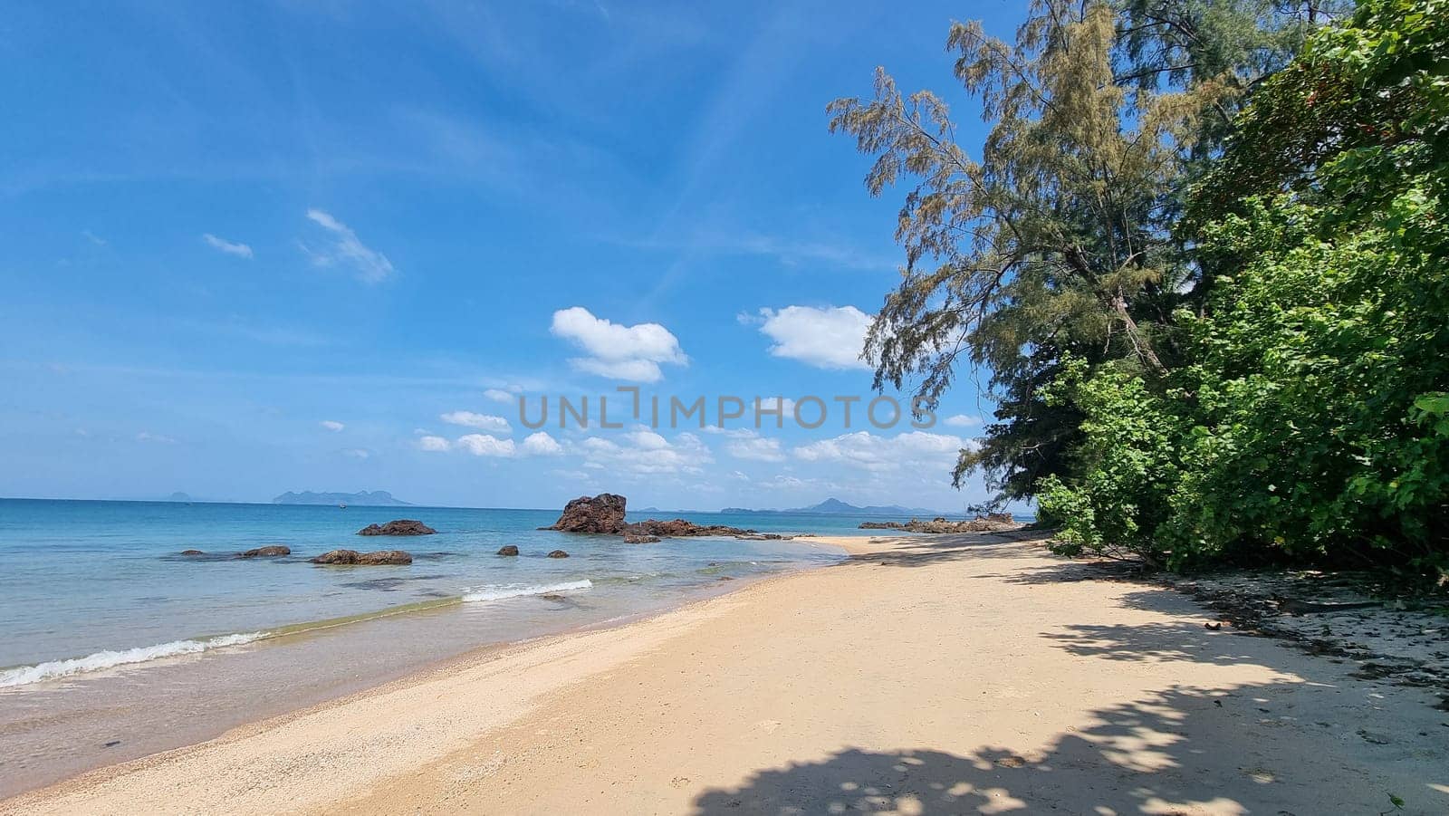 A sandy beach extends next to the sparkling ocean under a clear blue sky, creating a tranquil scene of natural beauty. Koh Libong Thailand