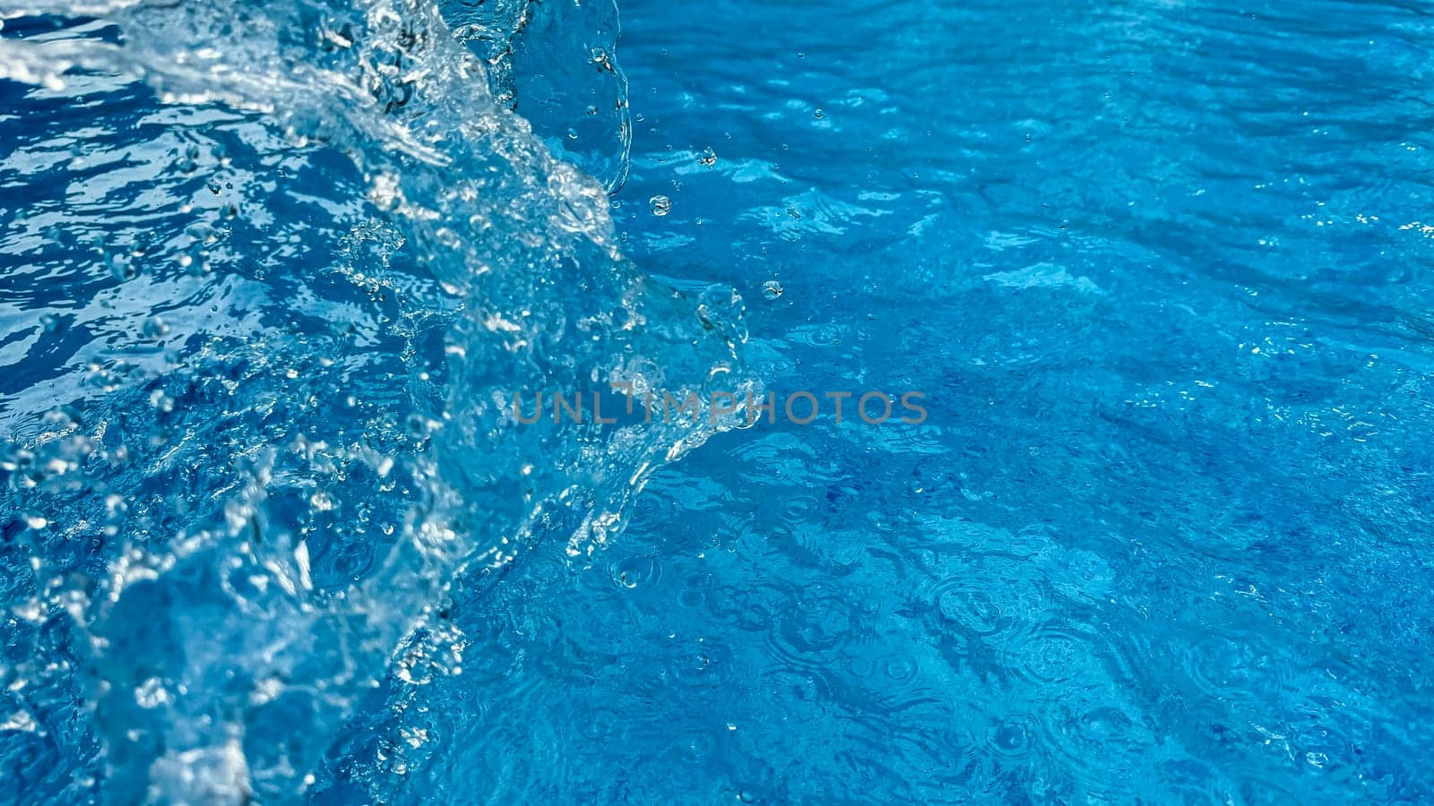 Background dynamic splash of clear water creating swirling wave in blue water with droplets suspended in motion. Clean water concept. High quality photo