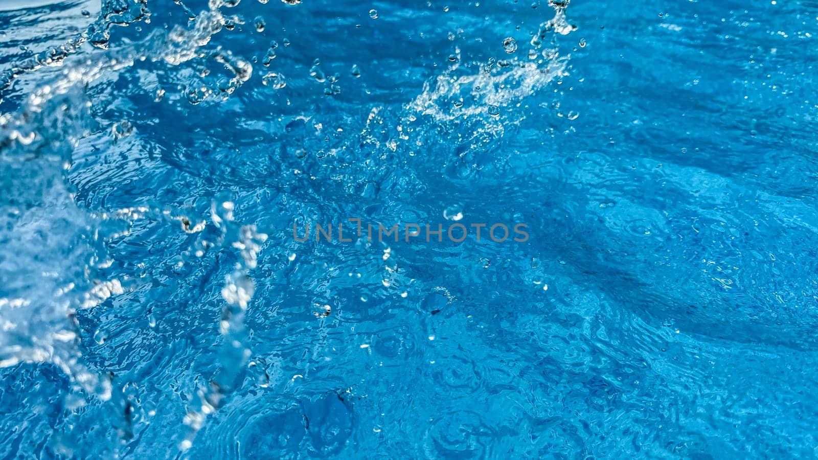 Background dynamic splash of clear water creating swirling wave in blue water with droplets suspended in motion. Clean water concept. High quality photo