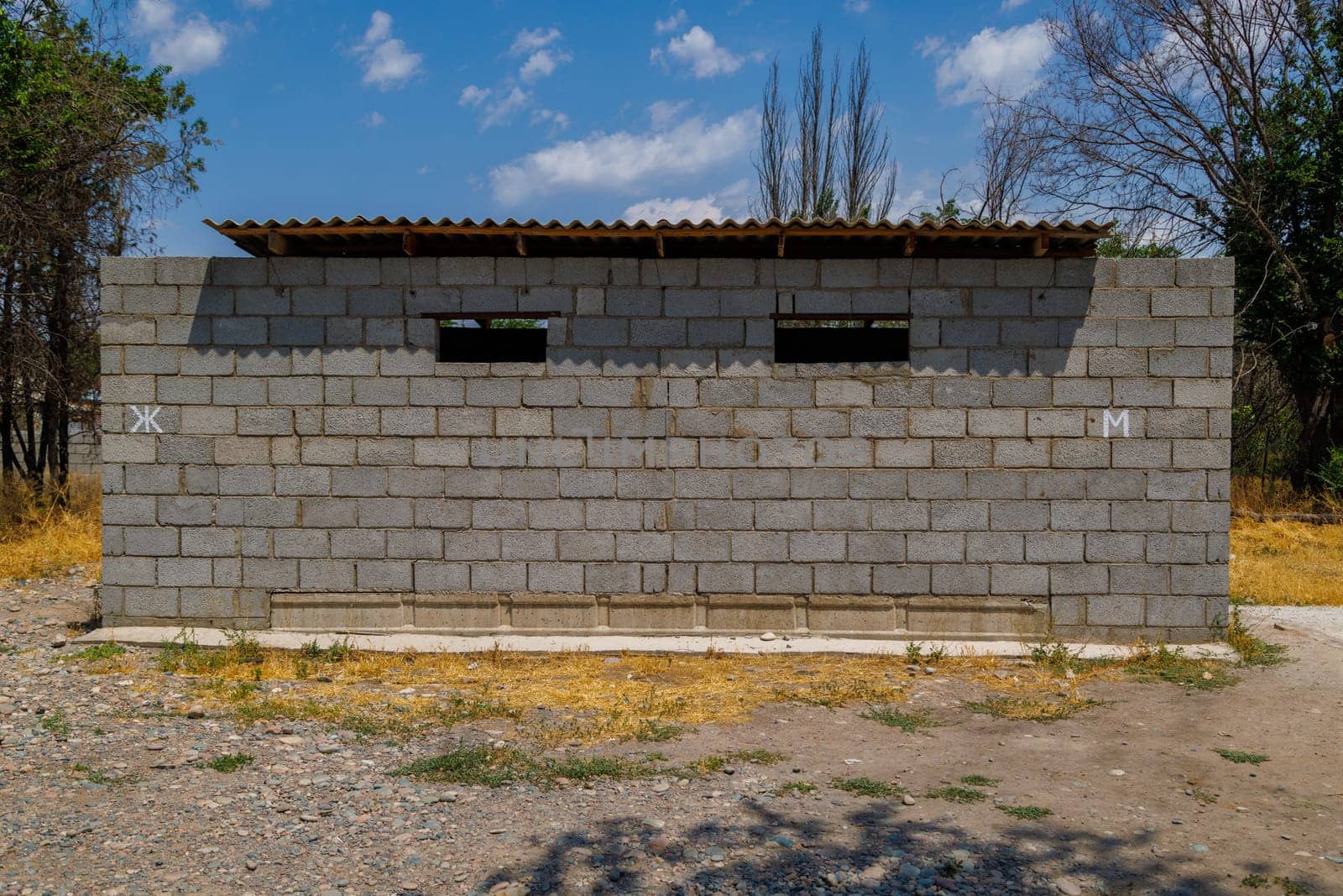 outdoor toilet made of gray cinder block bricks at sunny summer day by z1b