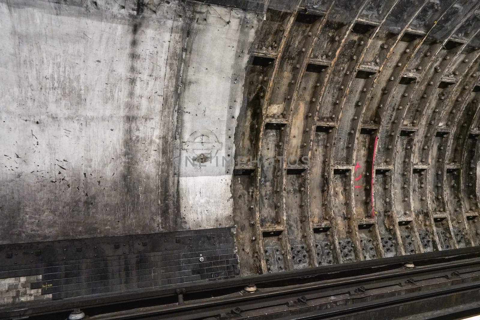 London, United Kingdom - February 02, 2019: Old dirty wall in tube train tunnel, missing London Underground logo on concrete