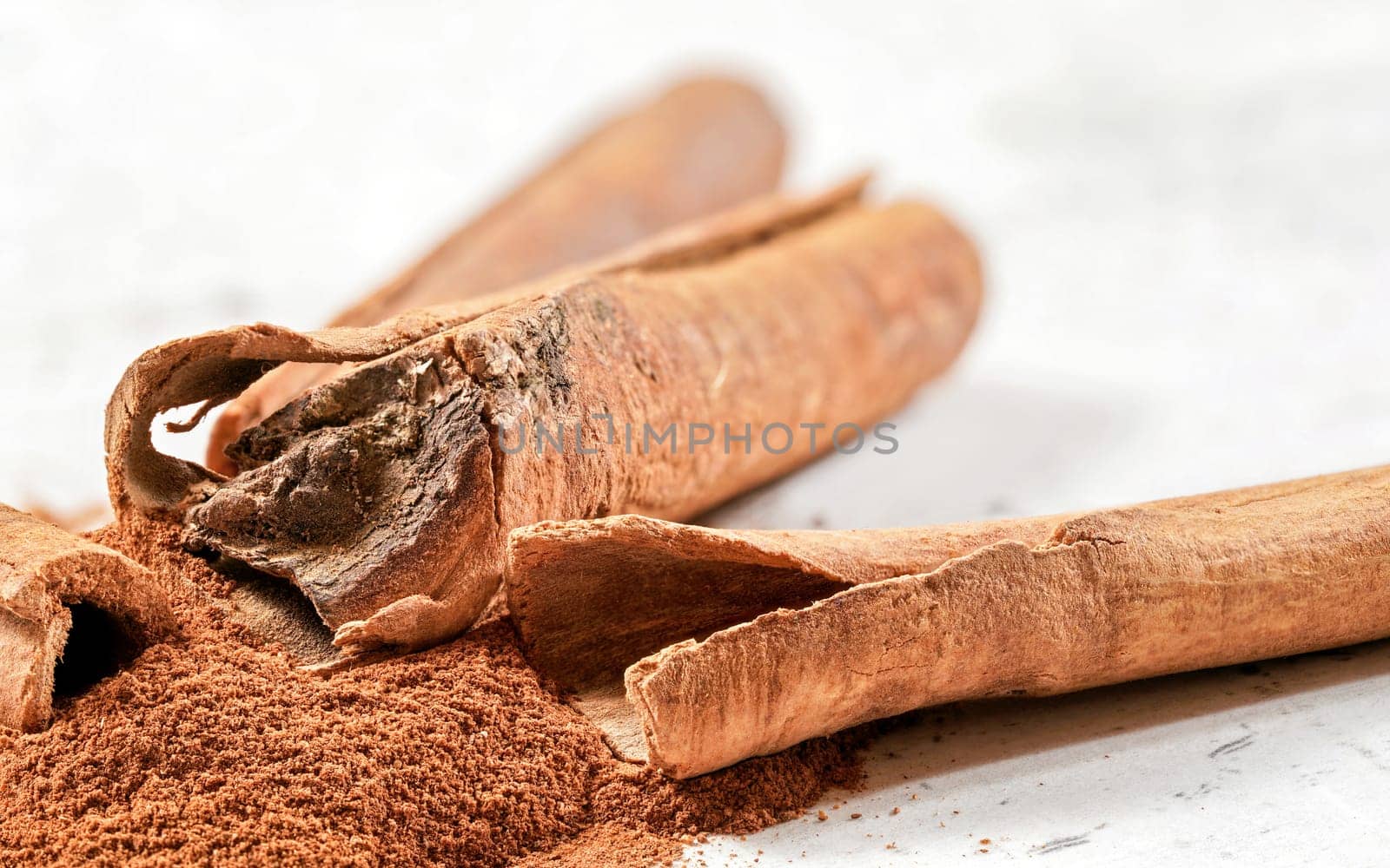 Closeup detail - Heap of cinnamon bark sticks on white stone like desk by Ivanko