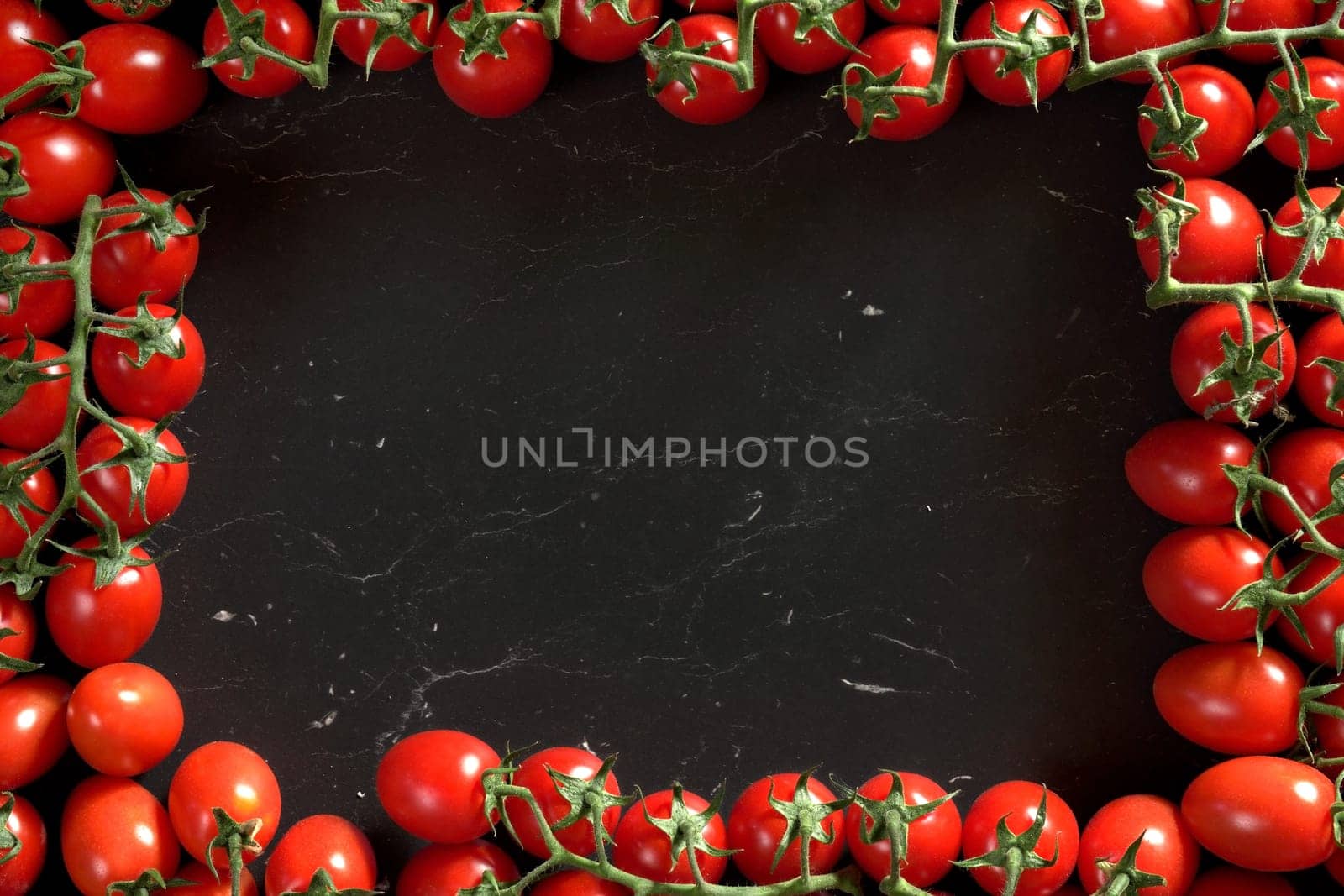 Red cherry tomatoes arranged in rectangular frame on black marble like board, view from above space for text in middle by Ivanko