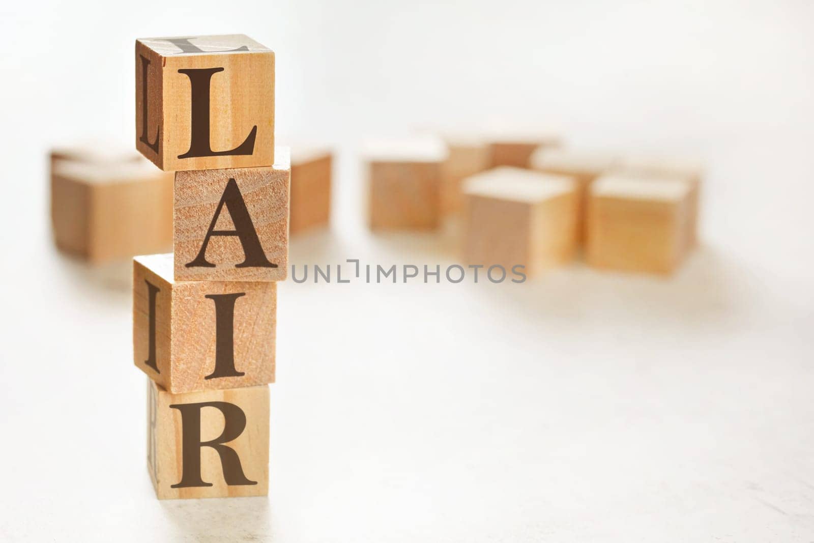 Four wooden cubes arranged in stack with text LAIR (meaning Listen, Acknowledge, Identify, Reversal) on them, space for text / image at down right corner