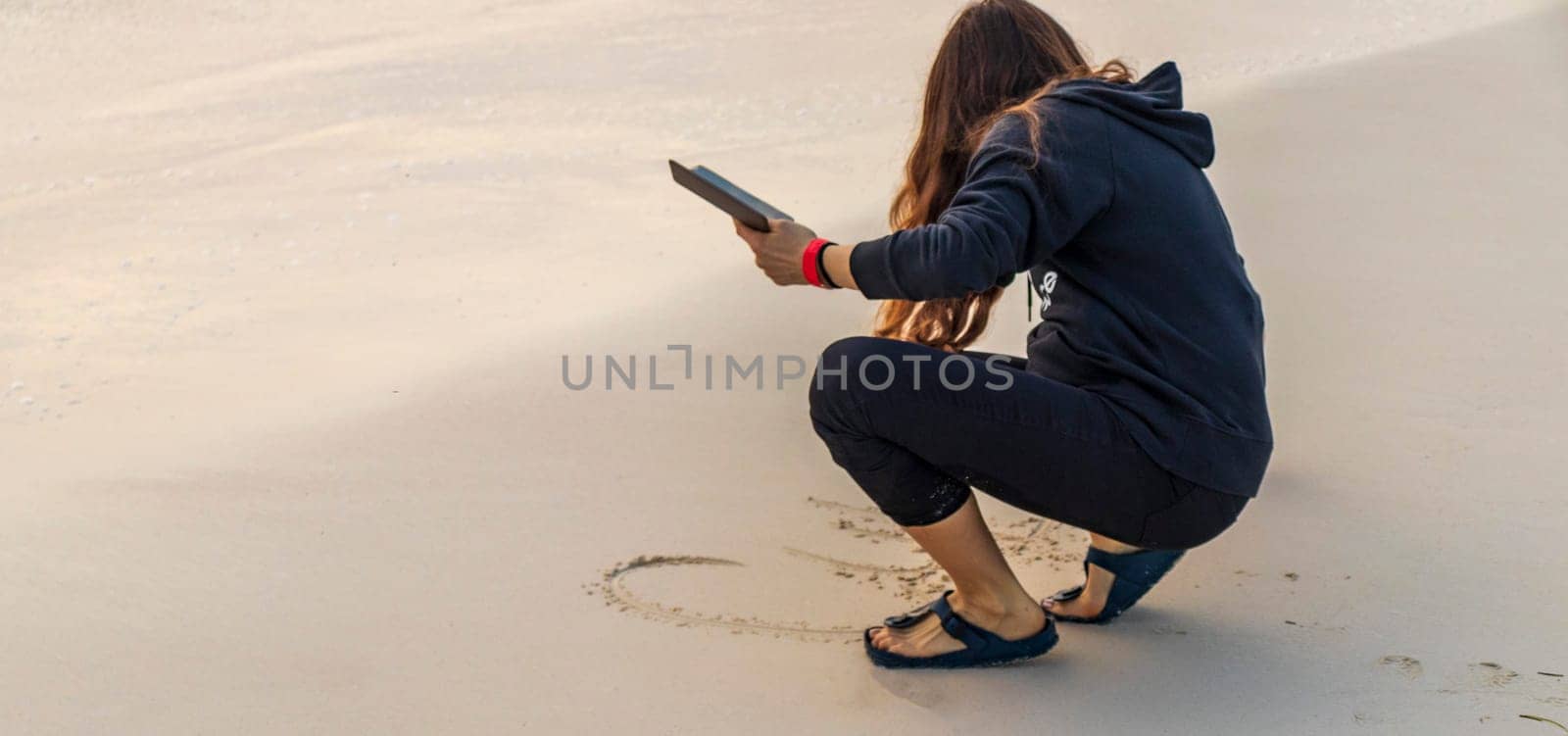 Shot of the woman by the sea shore with the cell phone, at sunrise hour