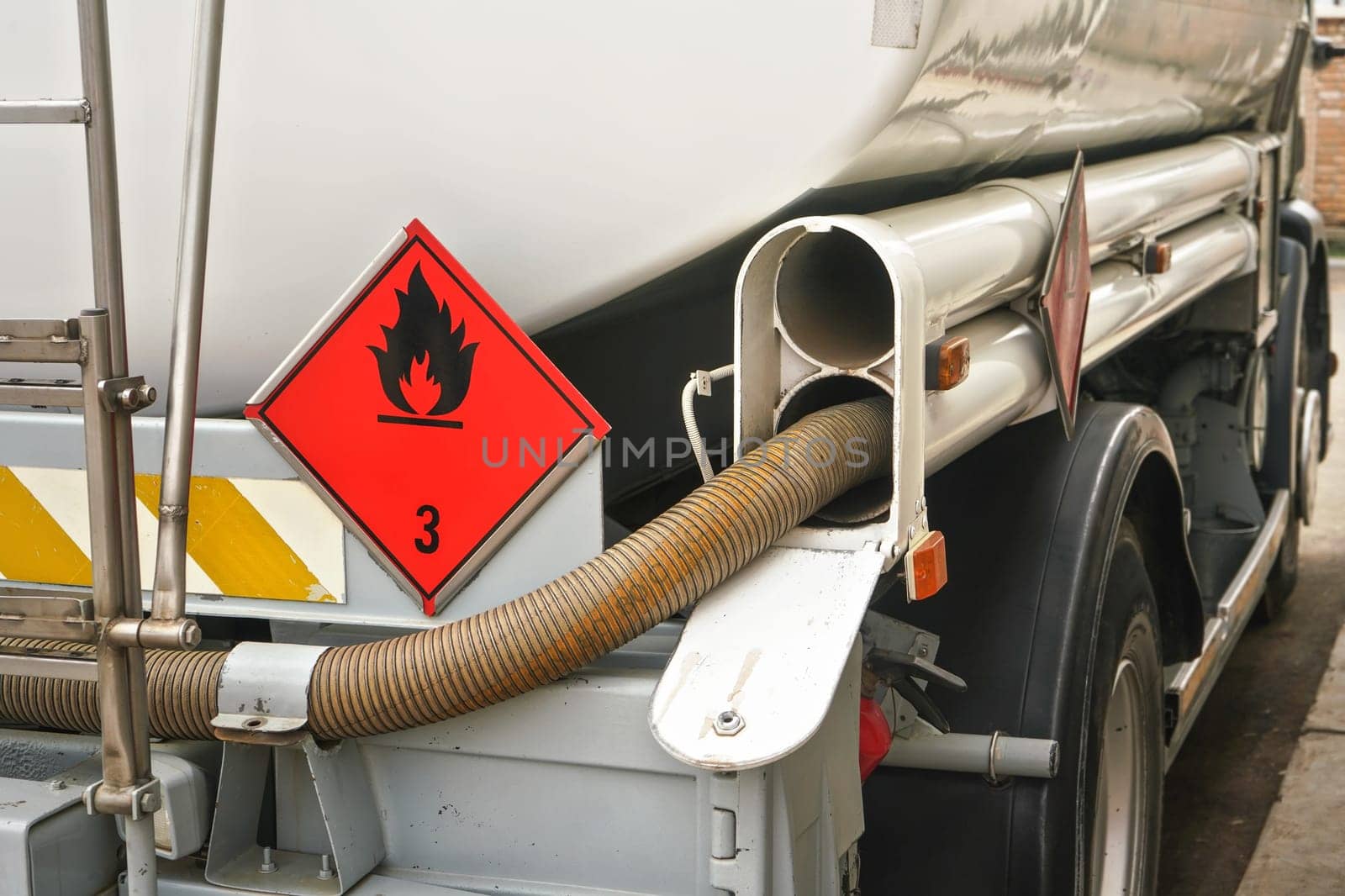 Red Warning hazmat Flammable class 3 liquid sign on back of fuel truck at petrol station