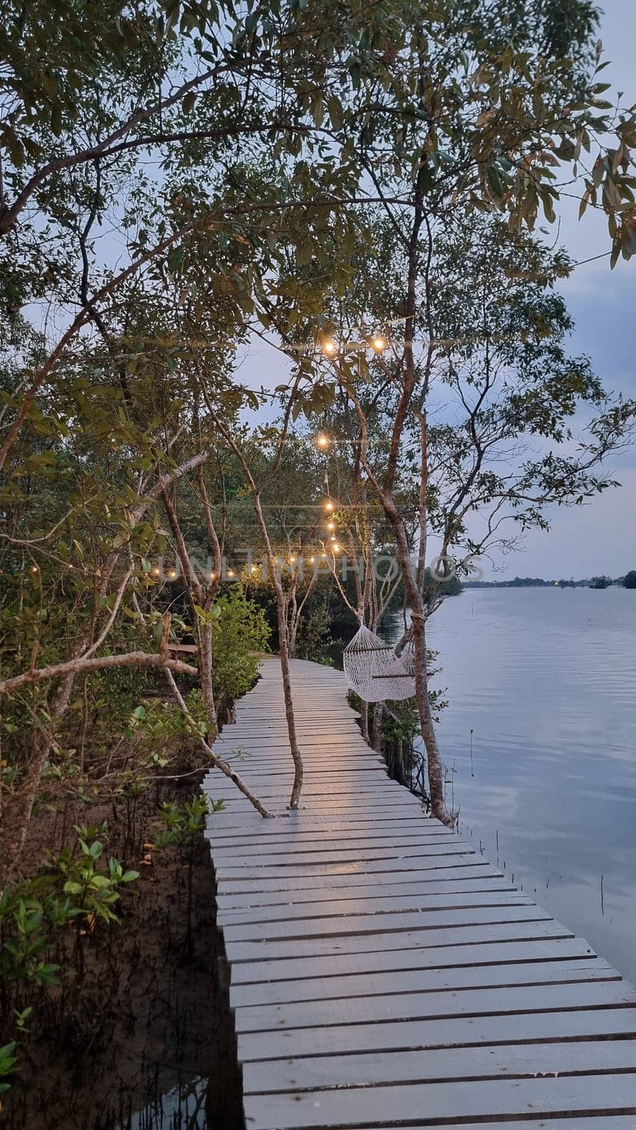 A picturesque wooden walkway winds its way through lush surroundings, leading to a tranquil body of water, inviting visitors to take a peaceful stroll by fokkebok