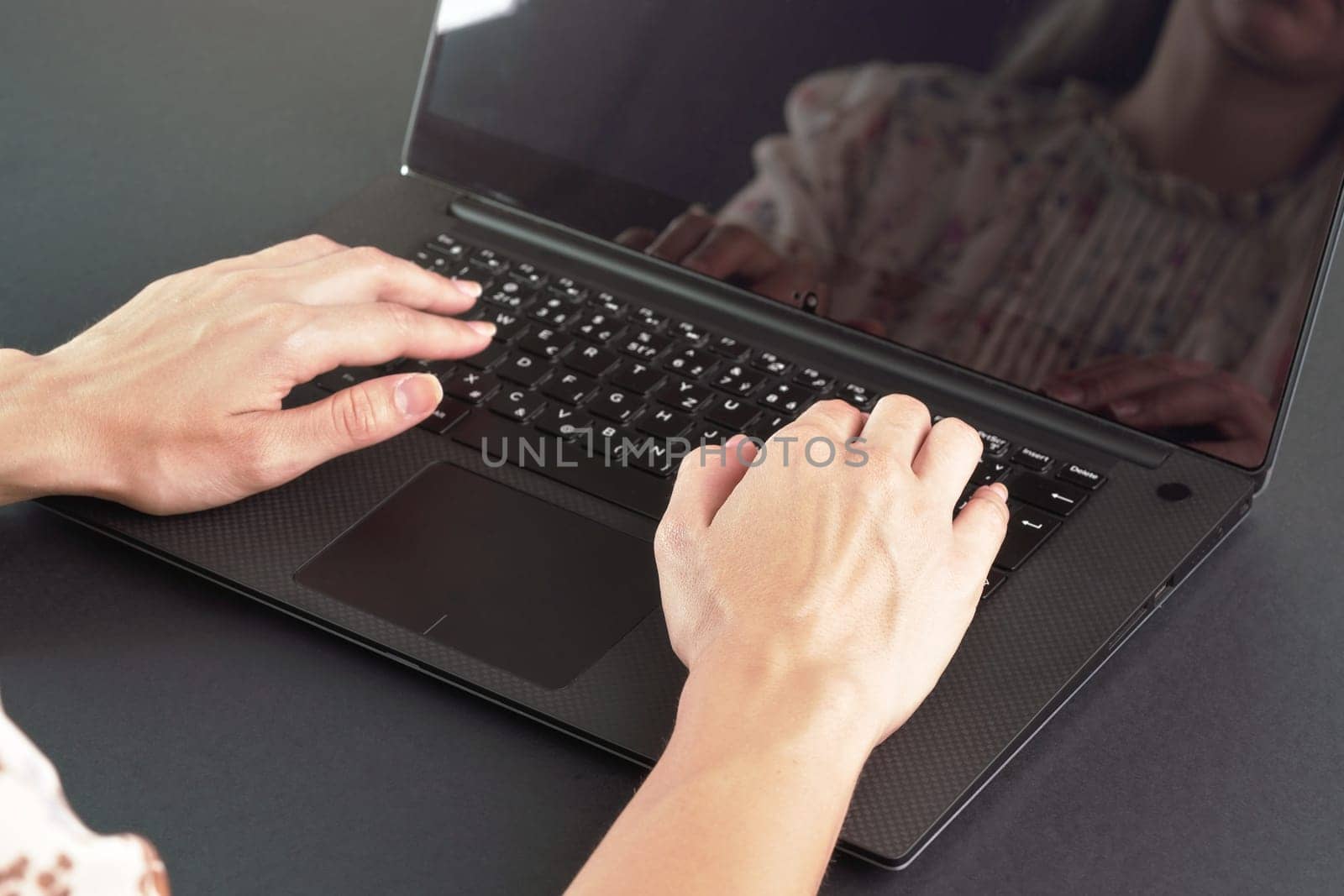 Young female working with laptop computer - detail on her hands over back keyboard by Ivanko