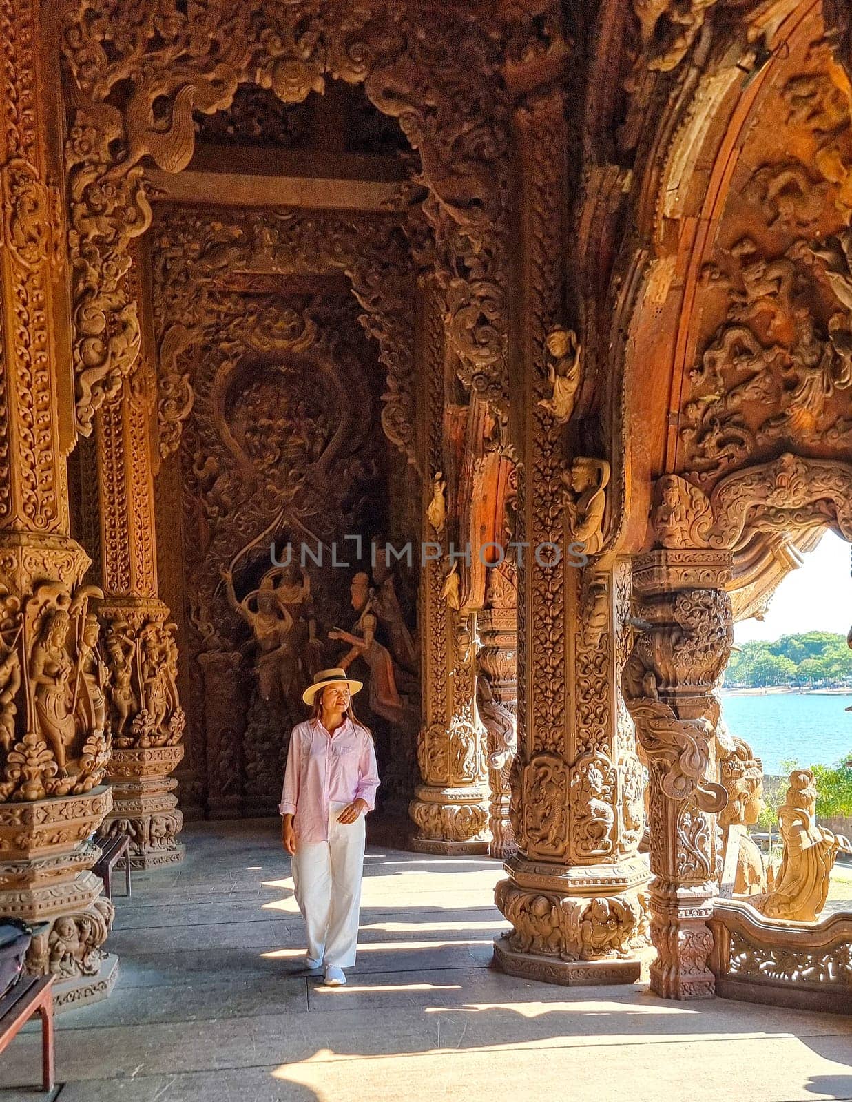 A man in a hat is casually strolling through a labyrinthine building, his silhouette framed against the intricate play of light and shadows by fokkebok